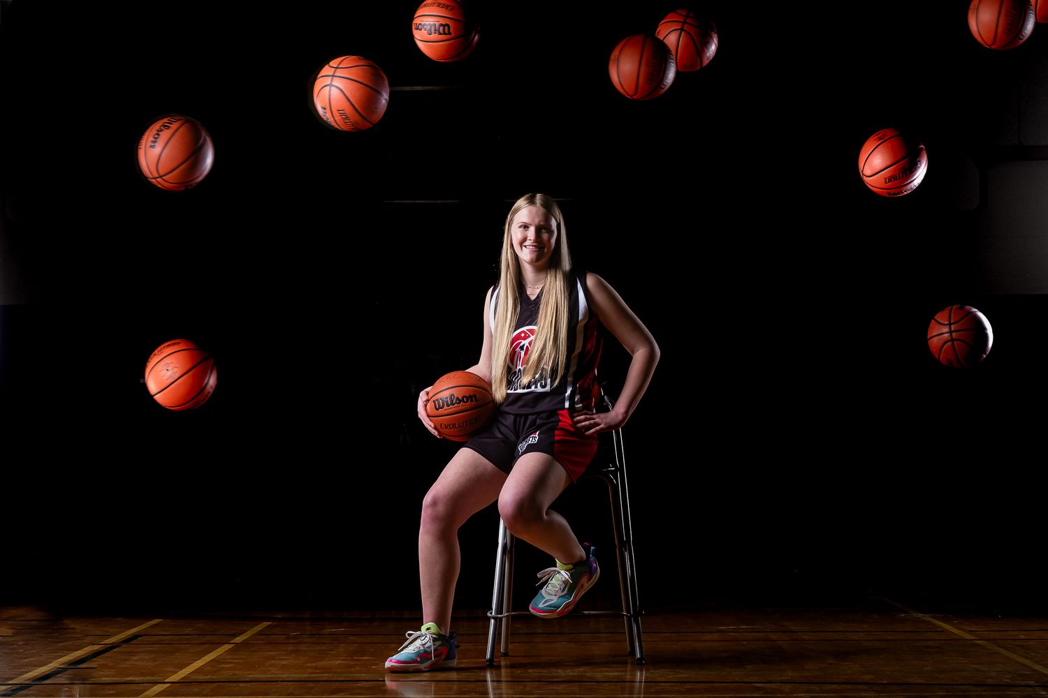 Competitive Basketball Player seated with balls flying overhead posed with cinematic lighting on the court
