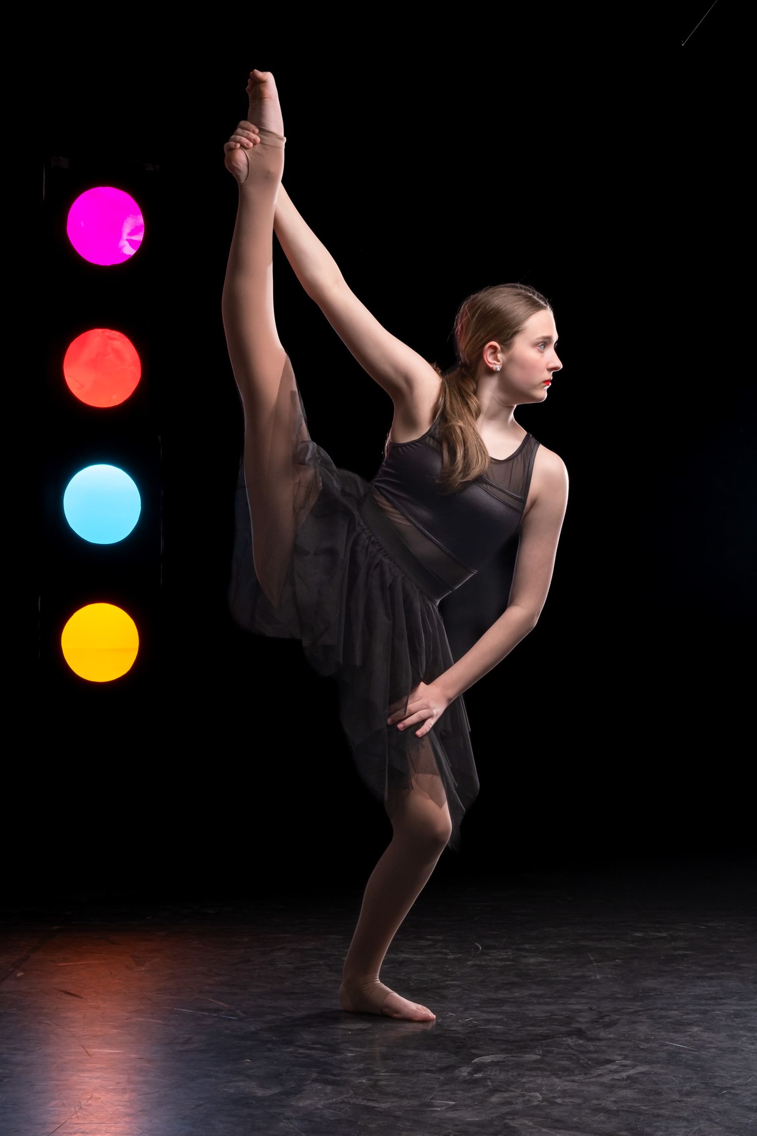Ottawa dance photography showing a dancer performing a leg extension against a dark background with colorful rim lighting.