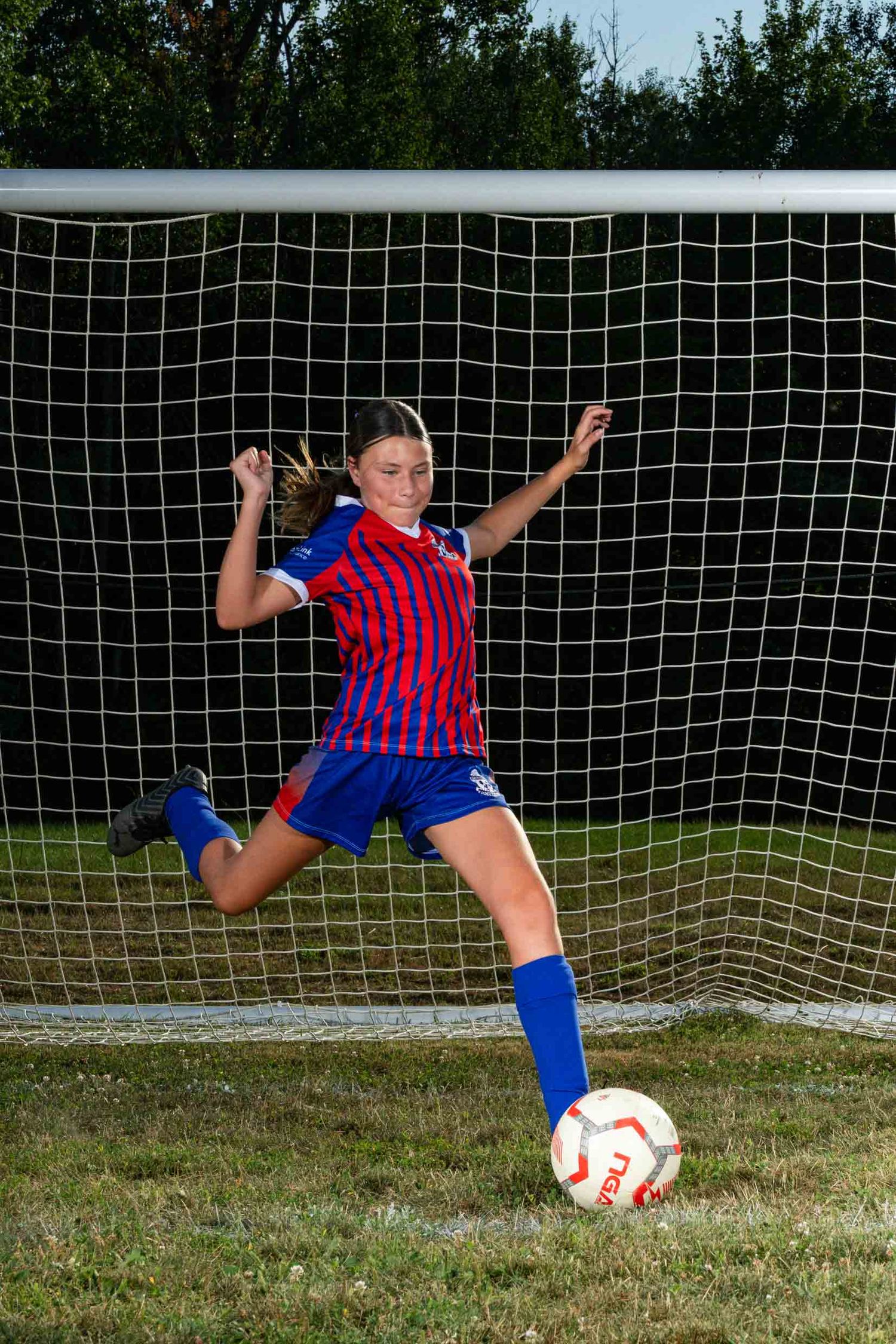 Action sports photography capturing a soccer player kicking a ball into the net during a photography session.