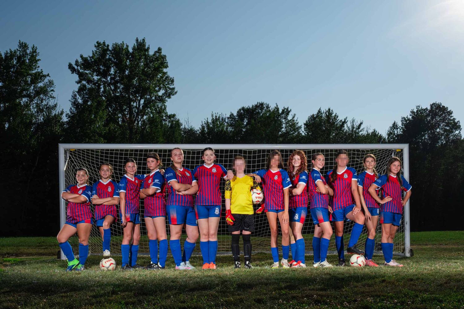 Professional soccer team photo on-pitch in front of the goal net, elite athletes, with professional outdoor lighting The Show Sports Media