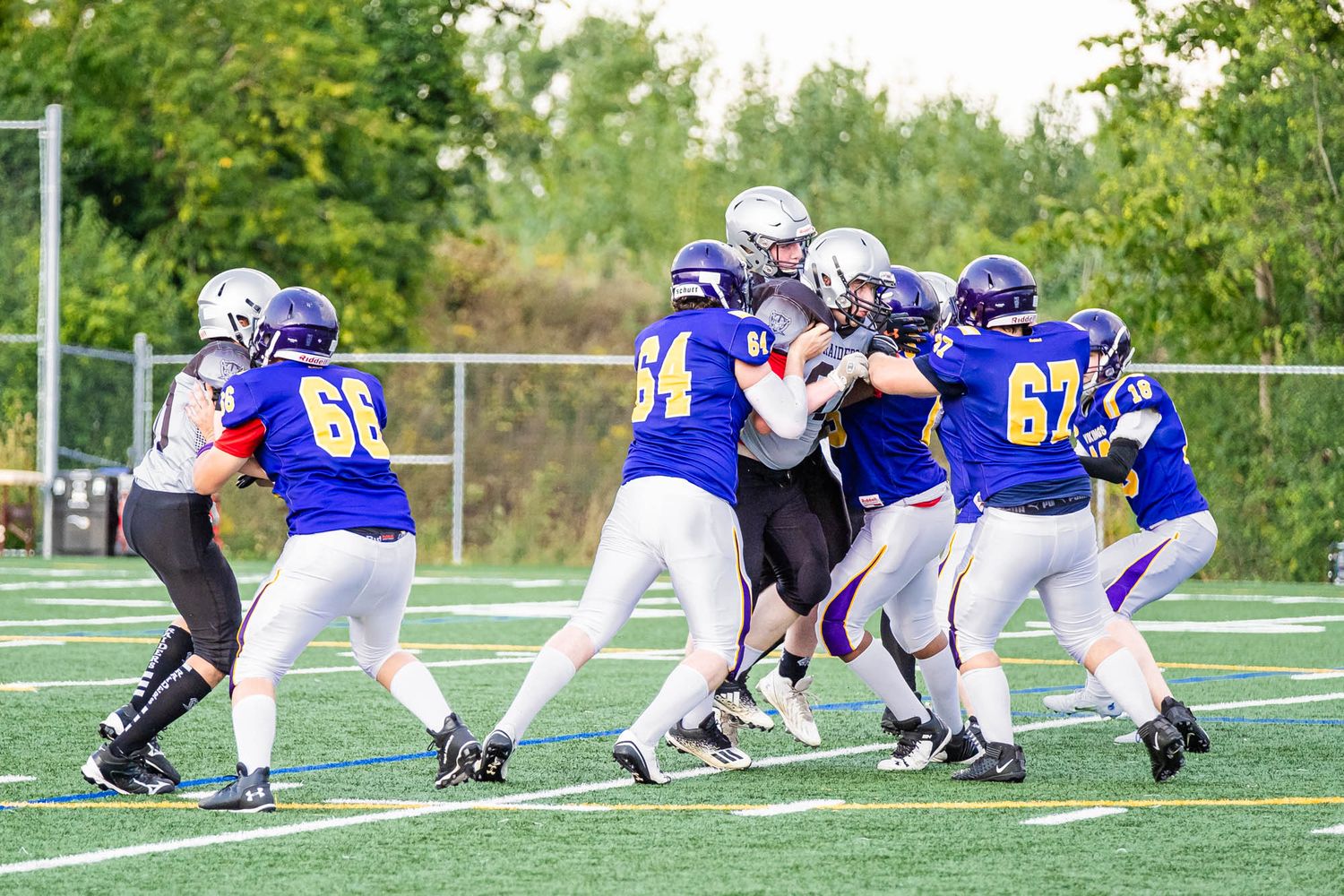 Action shot from an Ottawa youth football game with players in blue uniforms colliding with the other team in grey