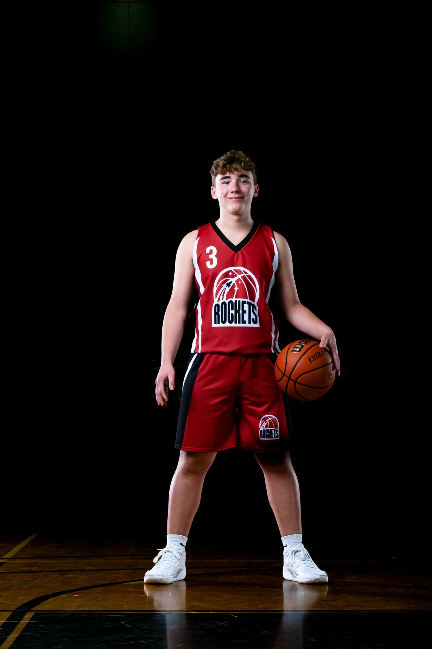 Elite Ottawa sports photography media day feature showing a moody, cinematic portrait of a basketball player under dramatic rim lighting
