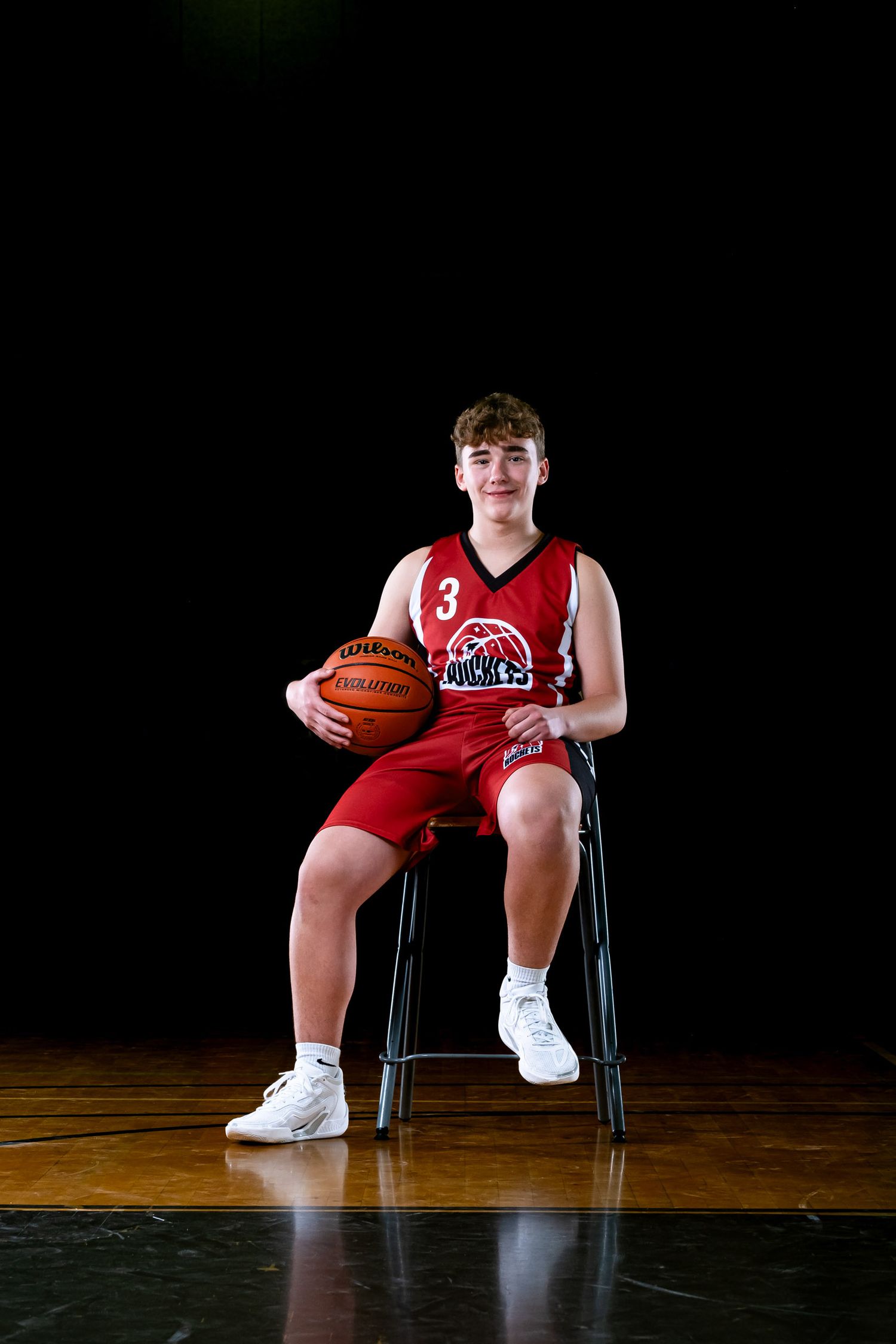Ottawa sports photography media day feature showing a moody, cinematic portrait of a basketball player sitting on a chair with a basketball