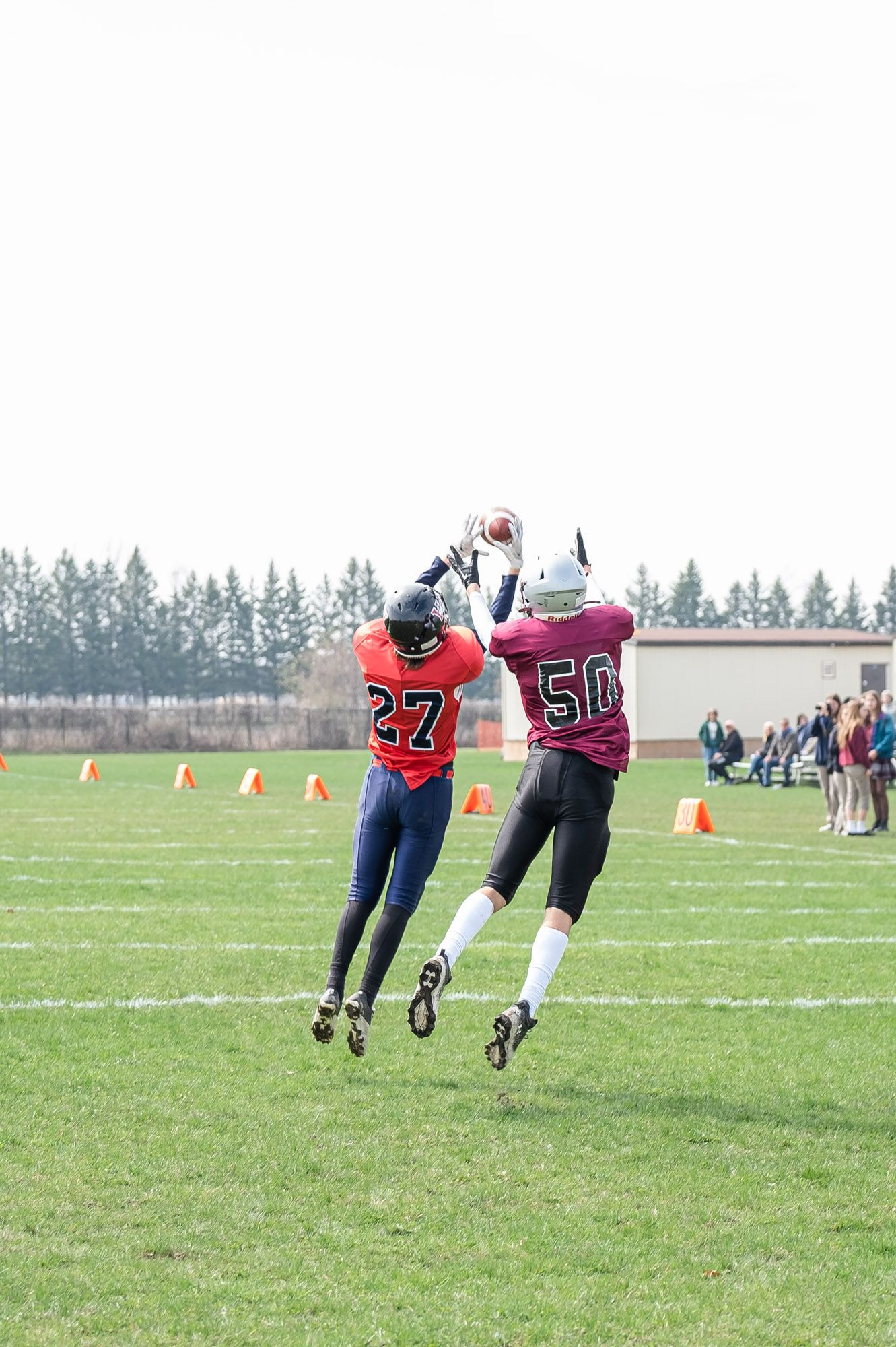 Action shot from an Ottawa youth football game with players in red uniforms jumping to receive during play.