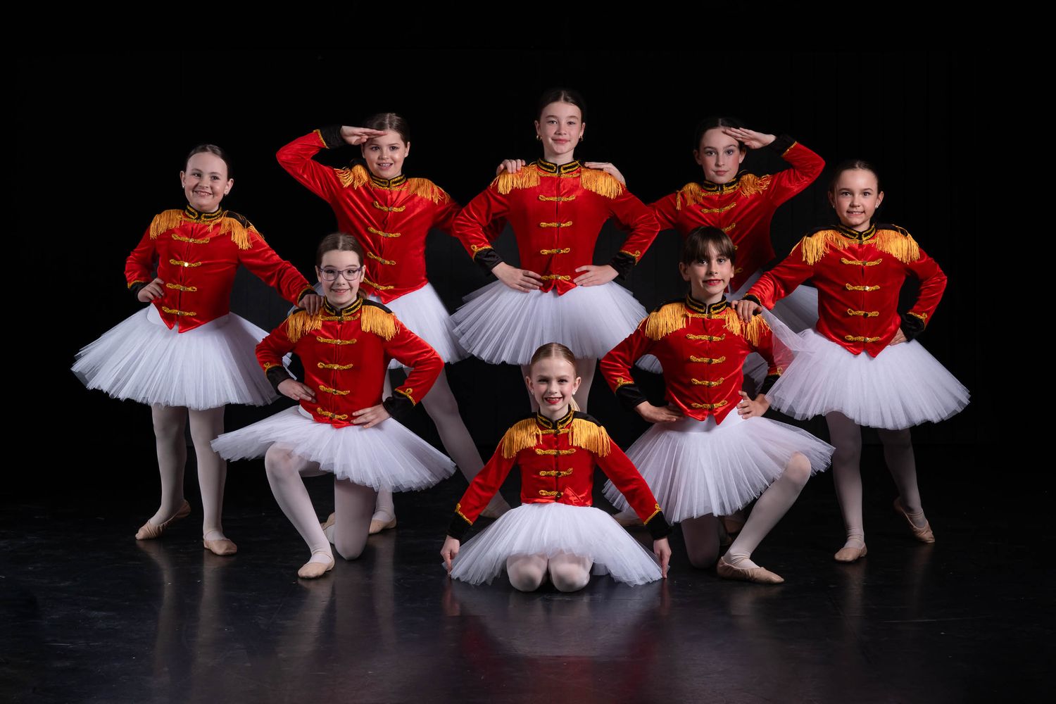 Group dance team photography featuring a synchronized floor pose with dramatic theatrical studio lighting.