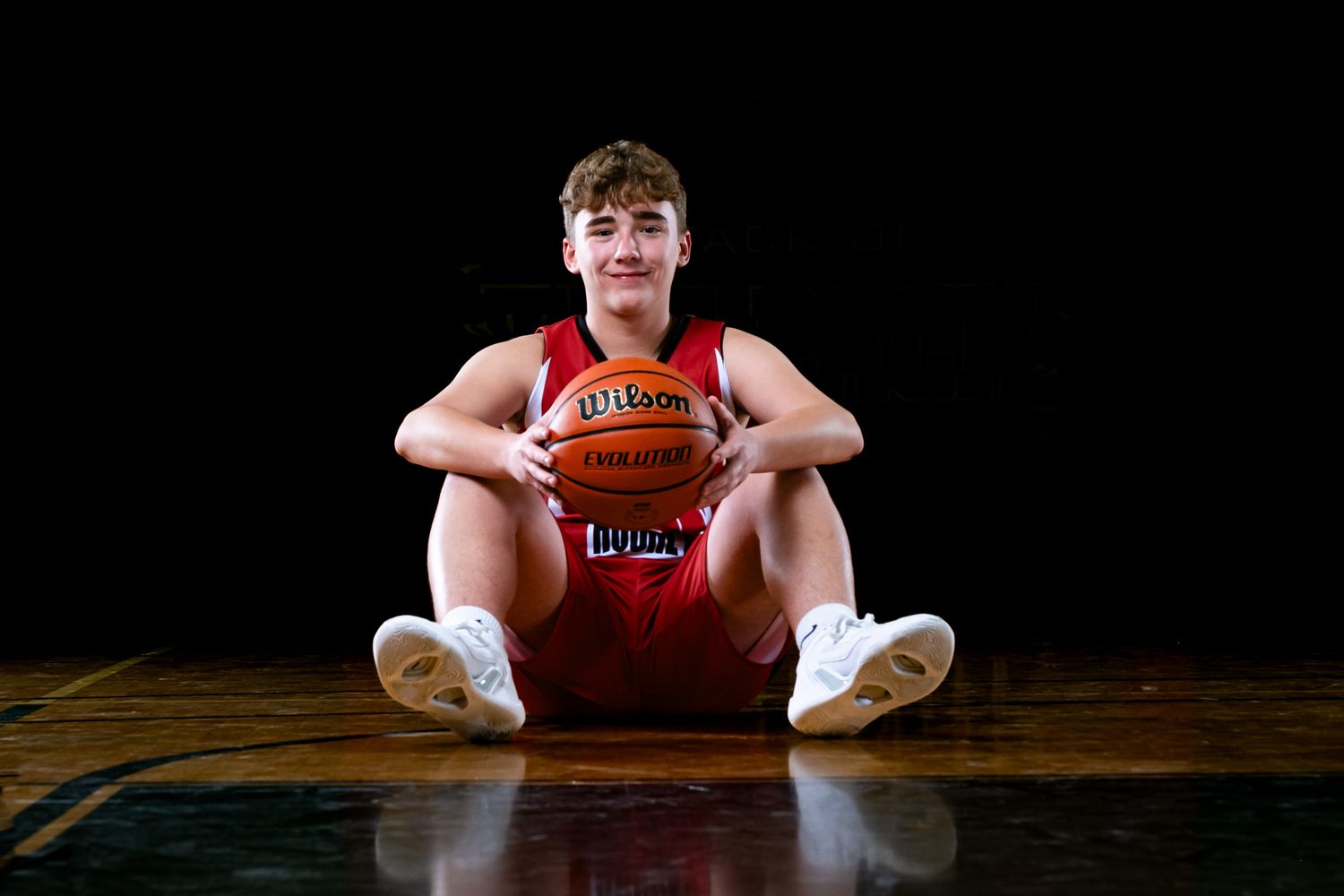 Ottawa sports photography media day feature showing a moody, cinematic portrait of a basketball player sitting under dramatic rim lighting