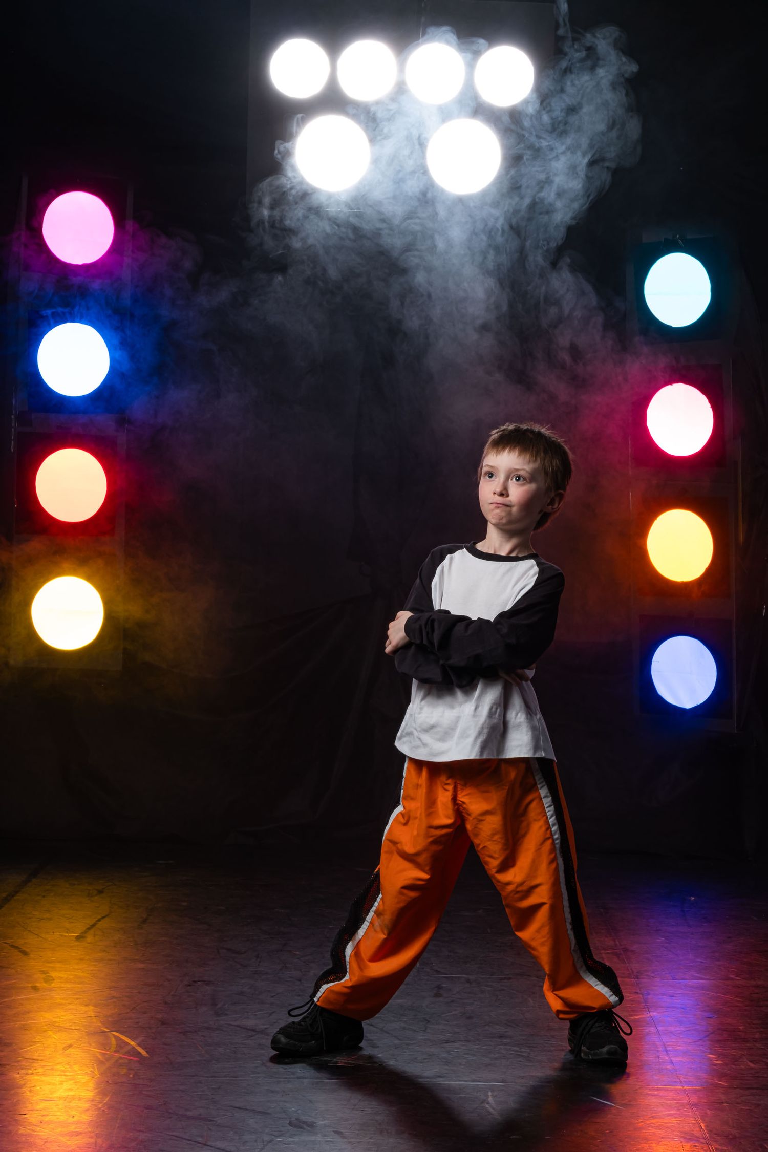 Dynamic studio dance portrait of a young dancer posing confidently under bright, multiple spotlights.