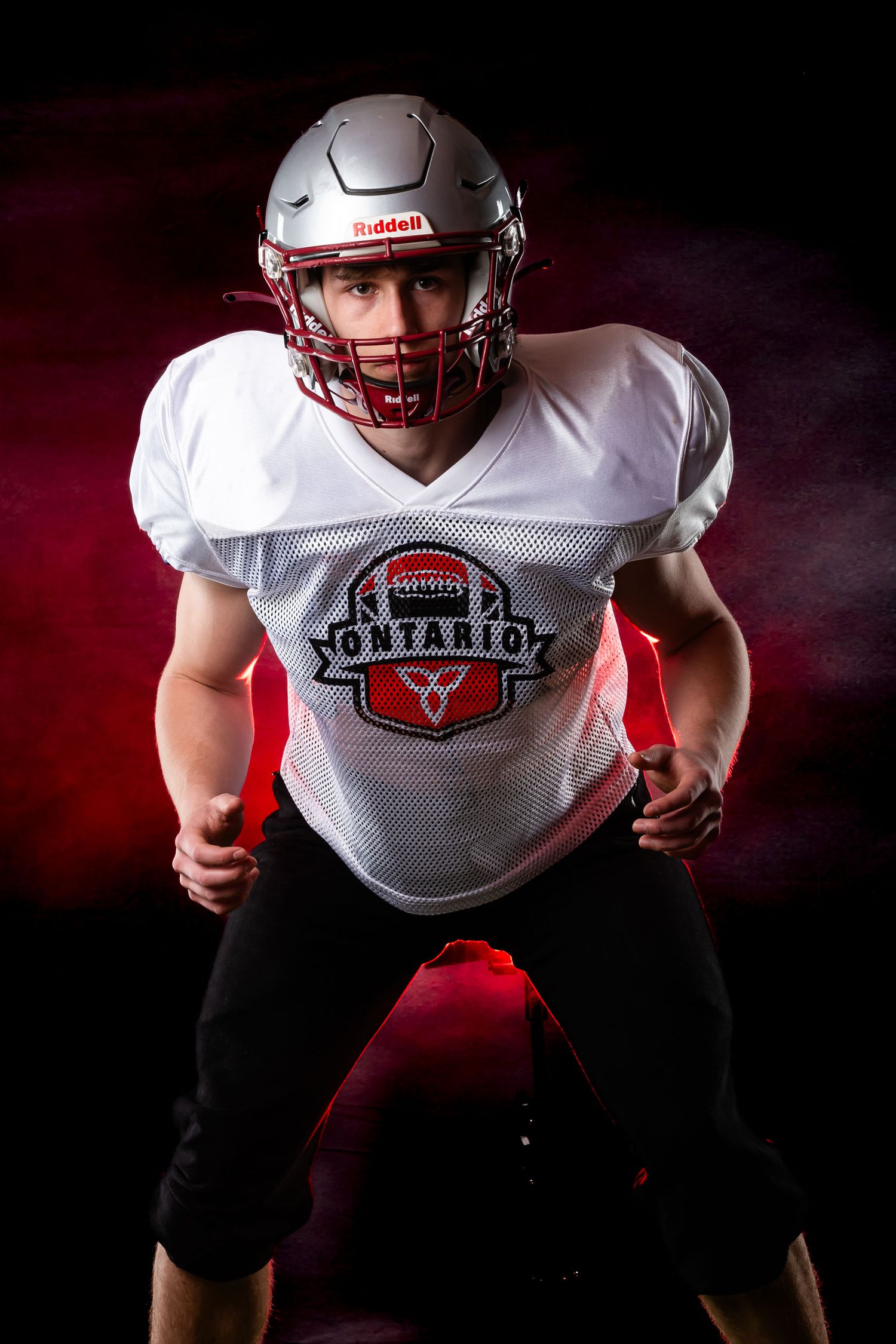 Dramatic Ottawa football photography media day portrait featuring intense red backlighting.