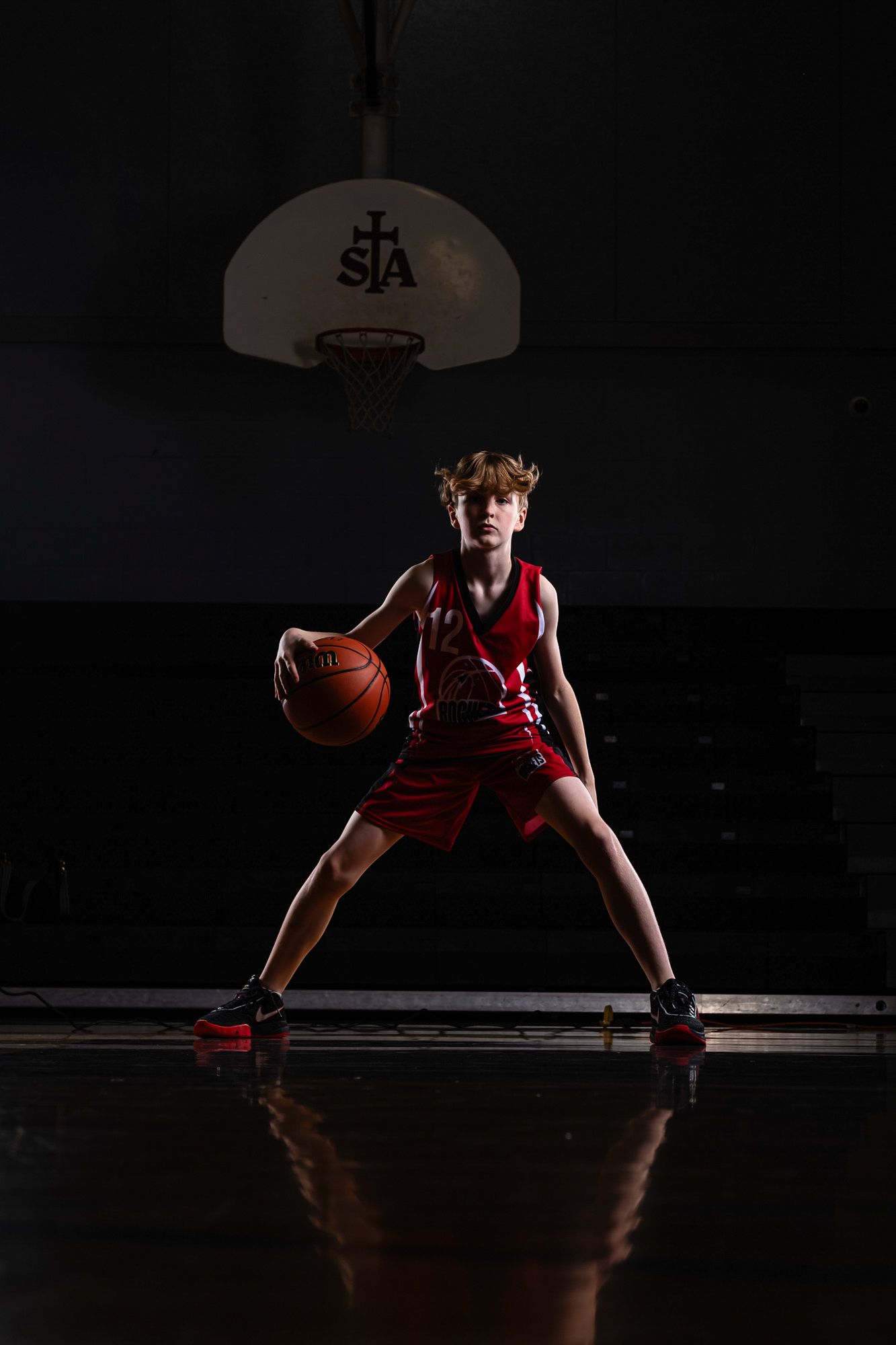 A male basketball player bouncing the ball in an action portrait using dramatic studio lighting and effects