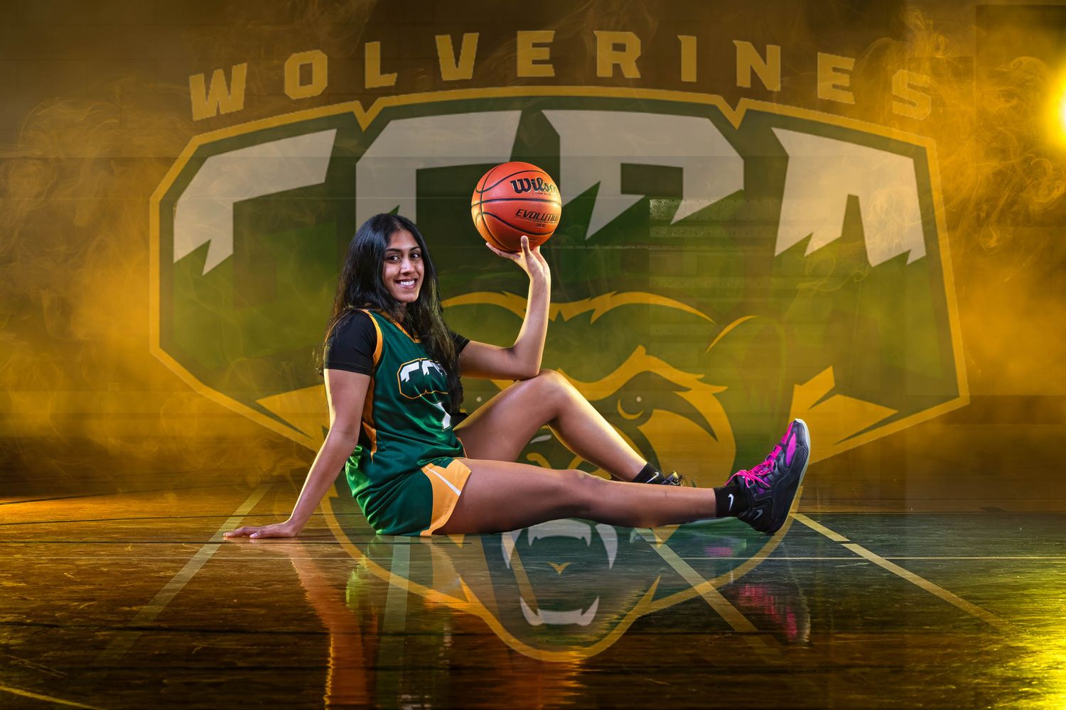 Cinematic sports portrait of a female basketball player number 7 seated on a gym floor court balancing a basketball on her fingertips.