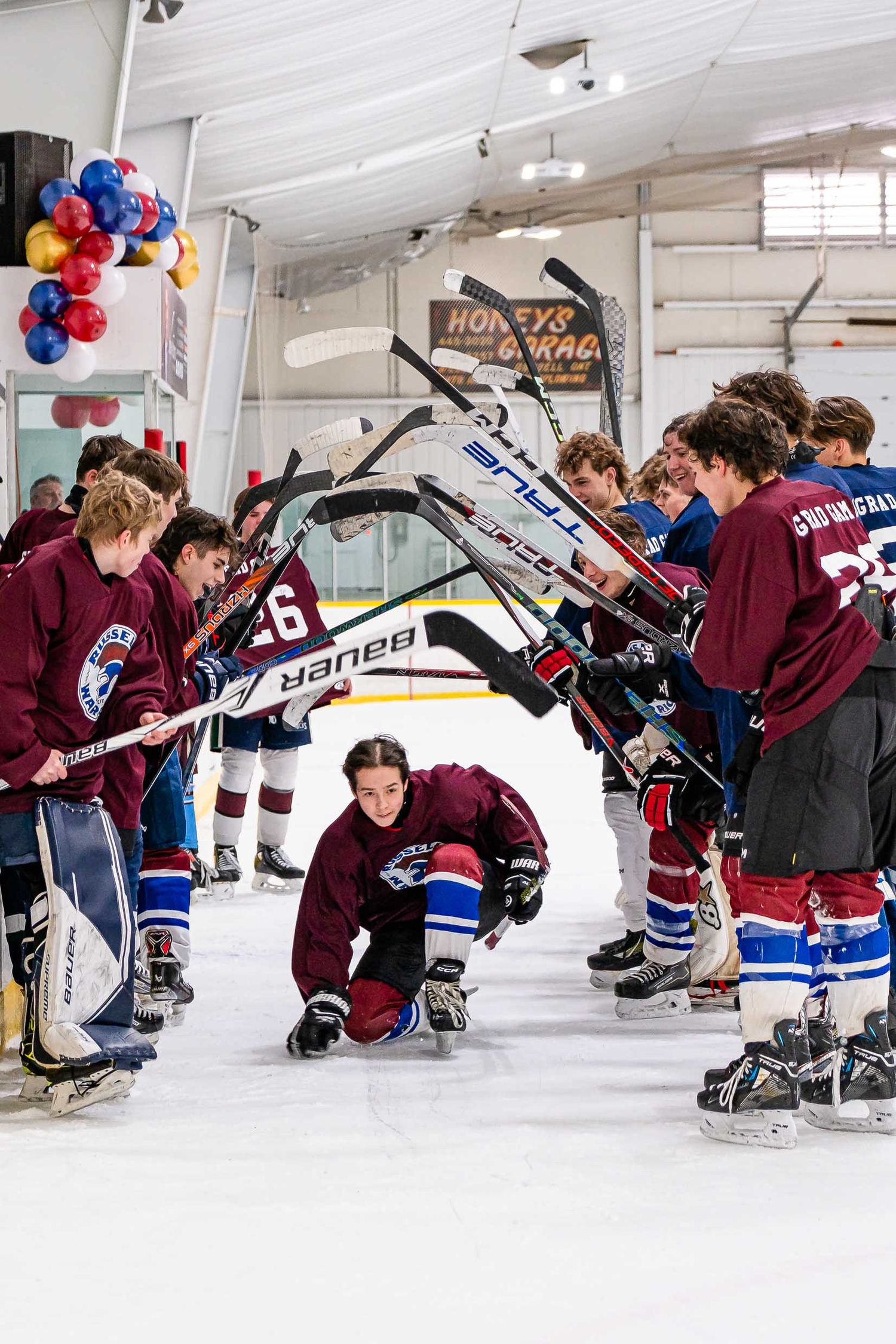 Fun moment on-ice photo of hockey team U18 Grad Game going through the hockey stick arch by The Show Sports Media