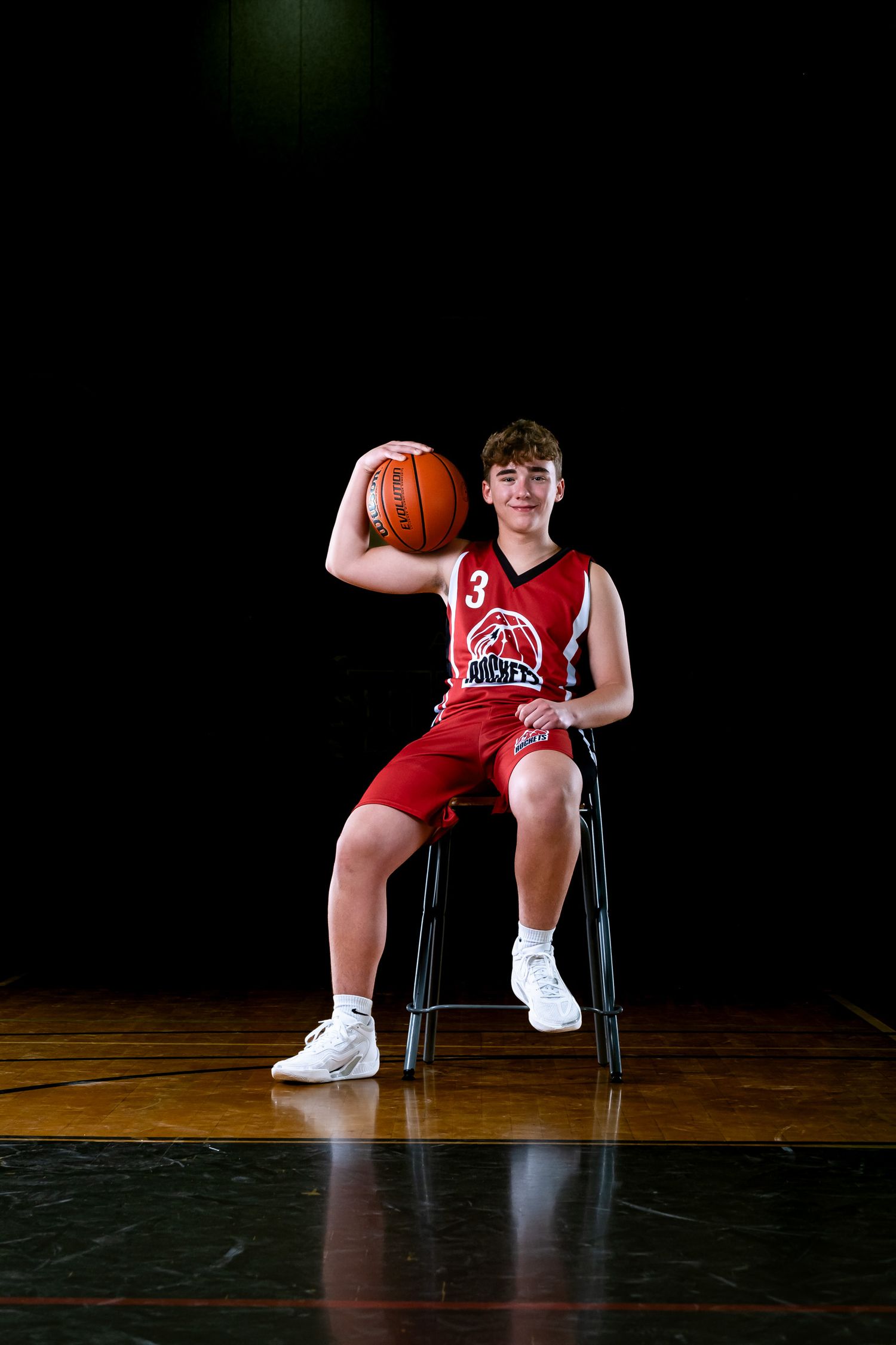 Ottawa sports photography media day feature showing a moody, cinematic portrait of a basketball player sitting on a chair with a basketball