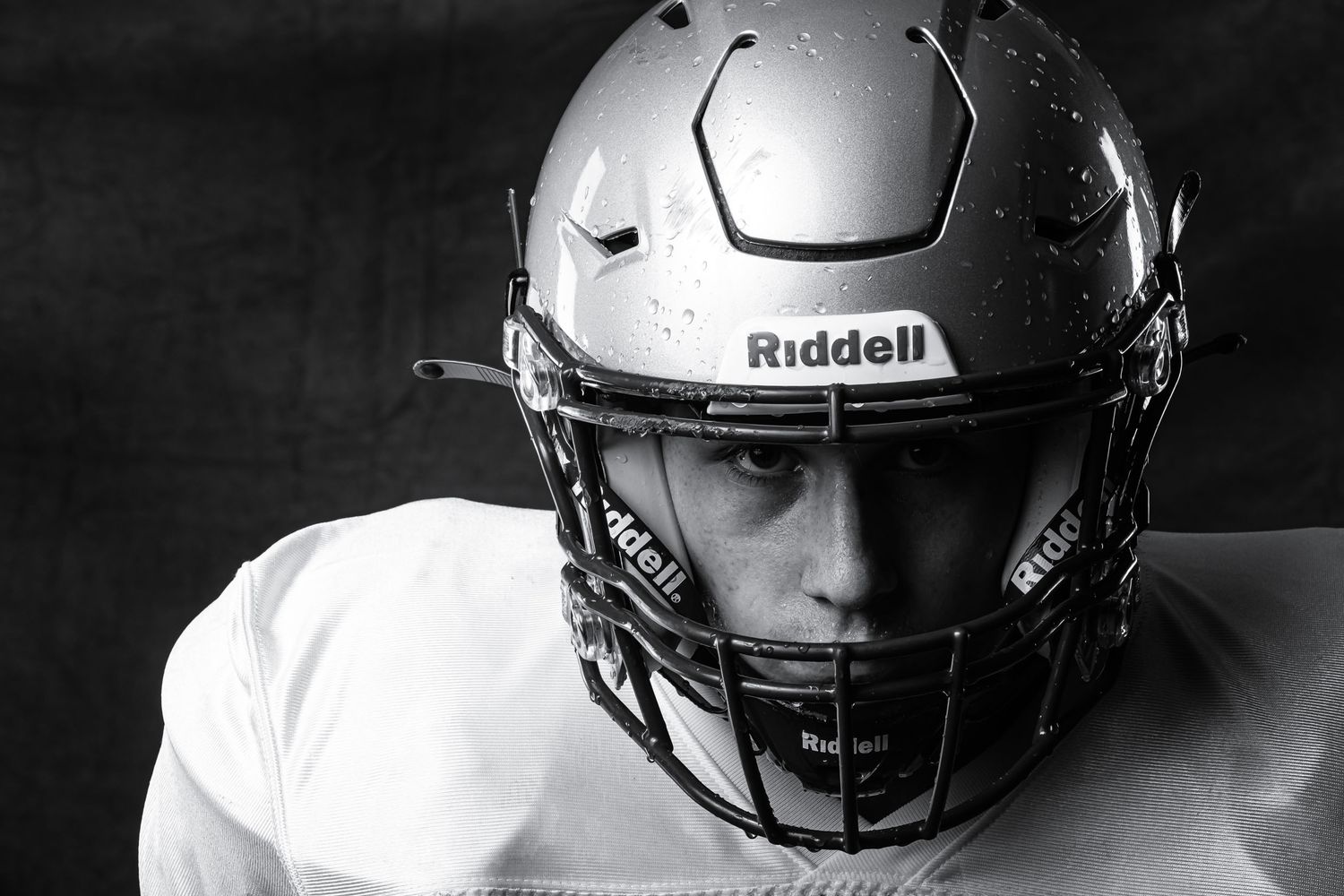 Intense close-up black and white football portrait showcasing a player wearing a helmet during an Ottawa media day.