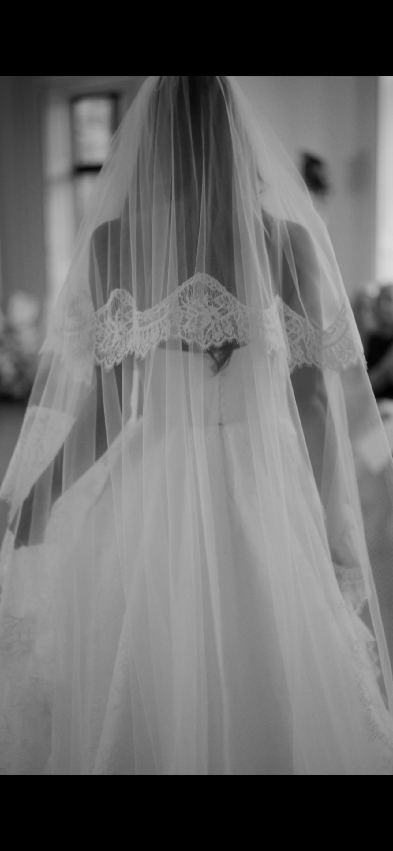 Black and white wedding photography showing flowing white veil details against a light background.