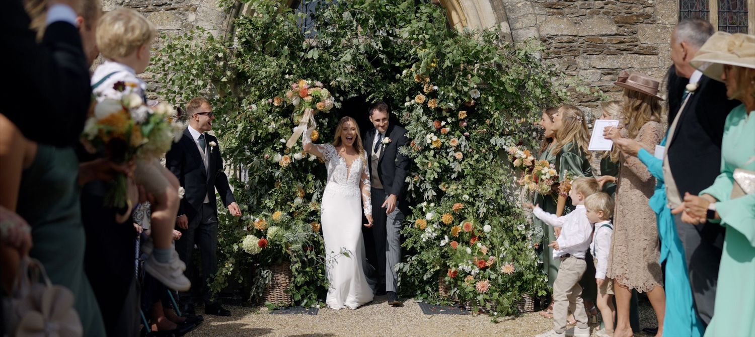 Newlyweds leaving Cotswolds church after traditional English countryside wedding ceremony