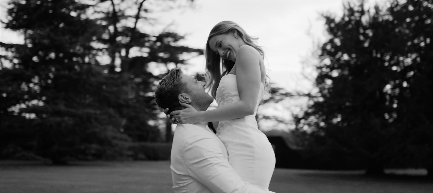 A romantic black and white silhouette of a wedding couple embracing outdoors during a tender moment on their wedding day at luxury UK venue