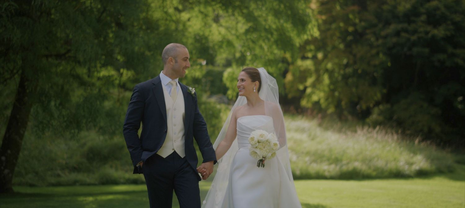 A romantic wedding couple shares a tender moment in a lush garden setting with natural greenery in the background.