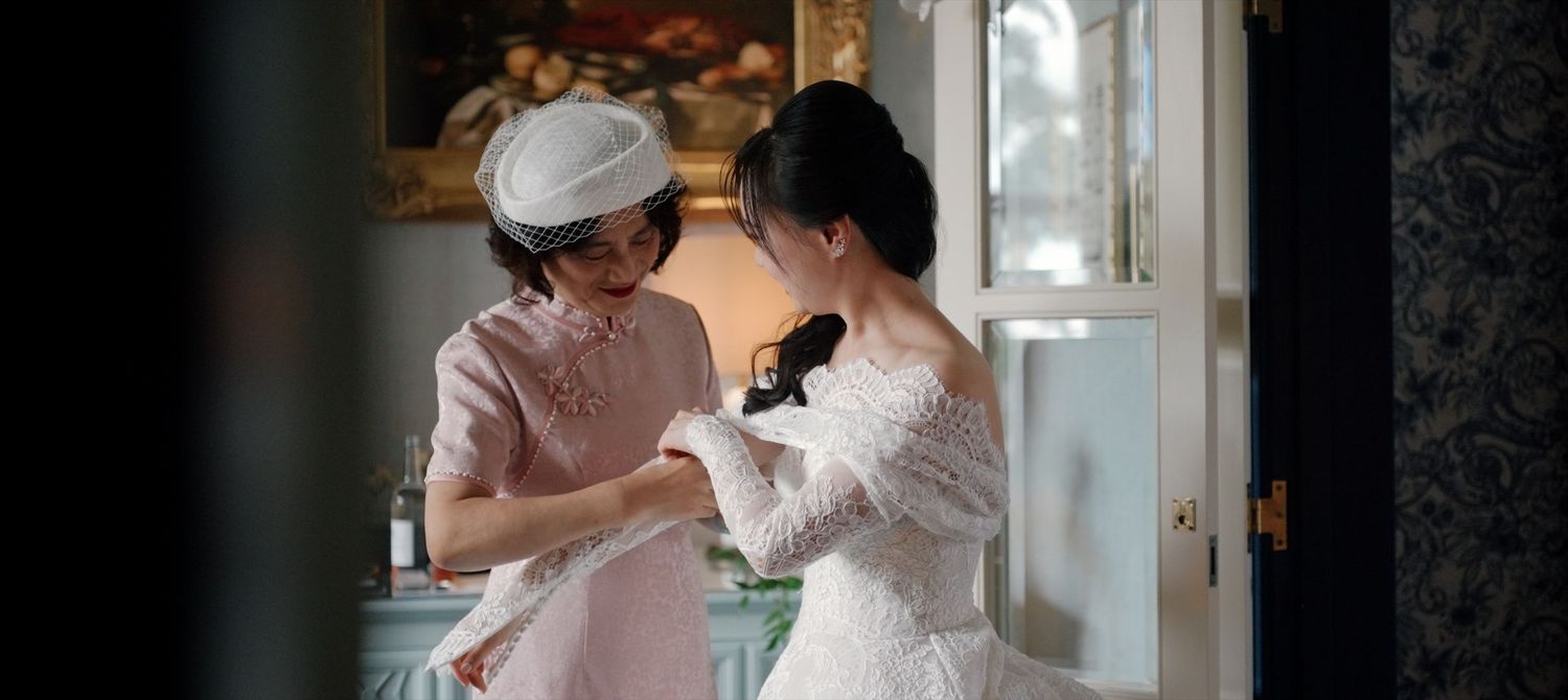 Mother of the bride helping bride dress during Oxford city luxury UK wedding