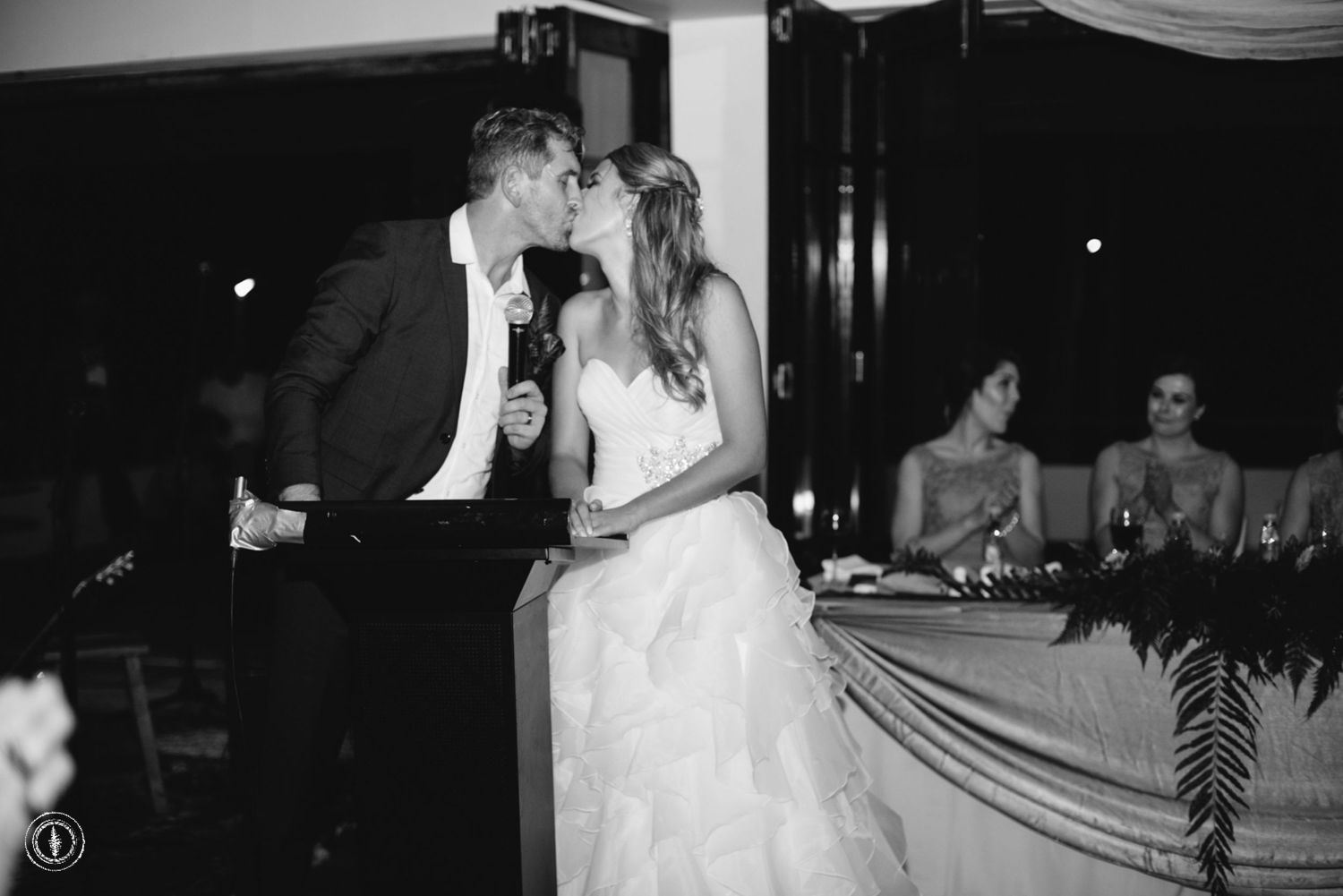 Black and white photo of a couple sharing a romantic moment during their wedding reception.