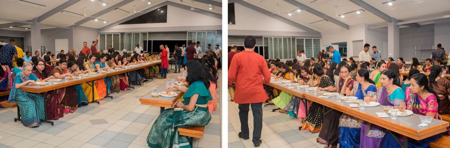 Large group dining setup at an Indian celebration with long tables and seated guests in colorful outfits.