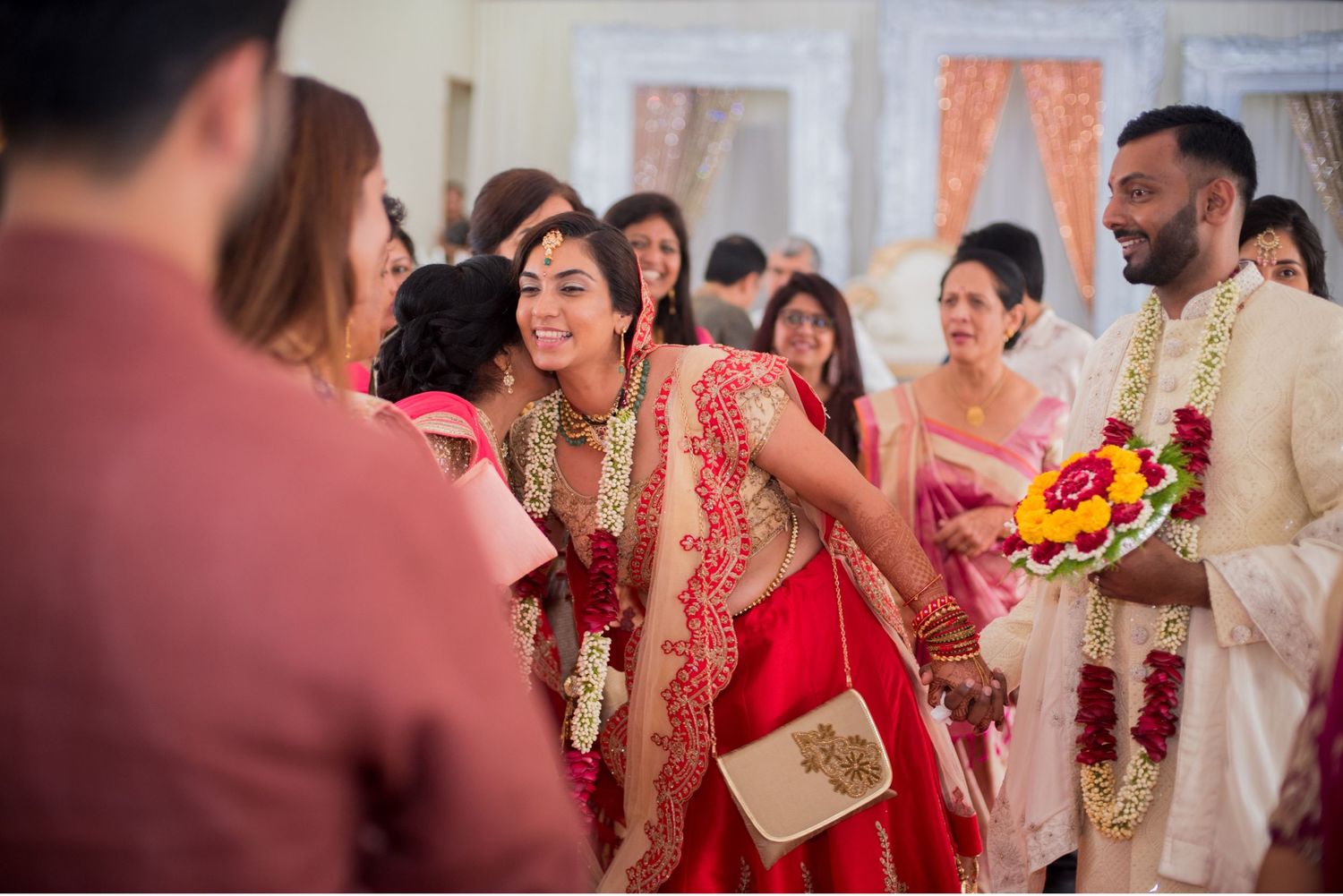 Celebratory indoor gathering with guests in vibrant traditional Indian formal wear.