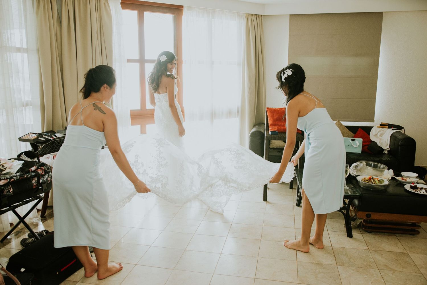 Women in white robes jumping playfully on a bed during wedding preparations.