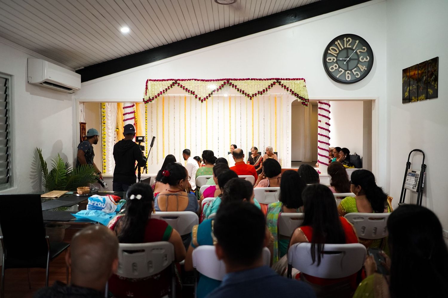 Wedding guests seated in rows watching a ceremony in an indoor venue.