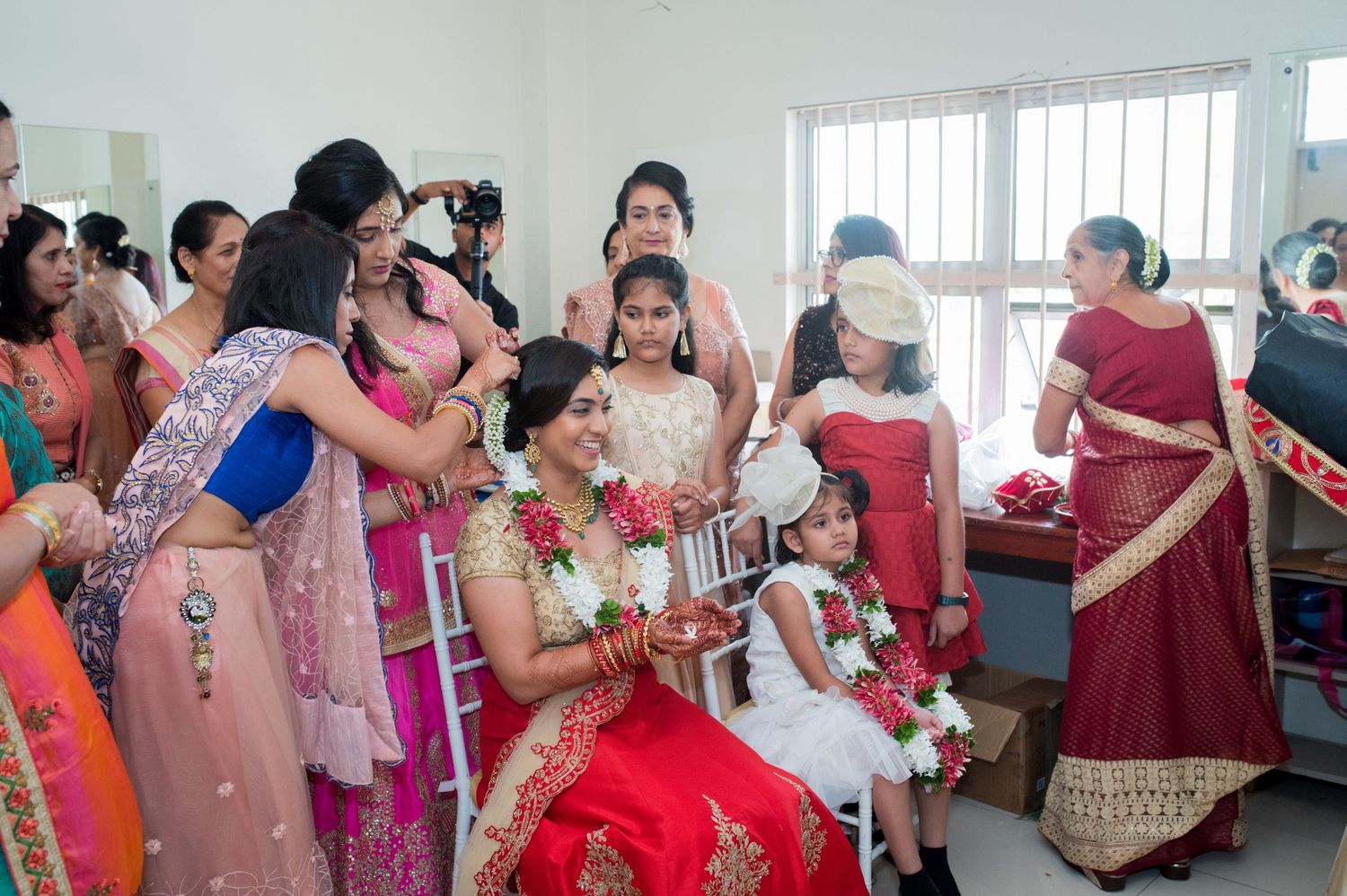 Wedding guests in colorful sarees gather around during a traditional ceremony.