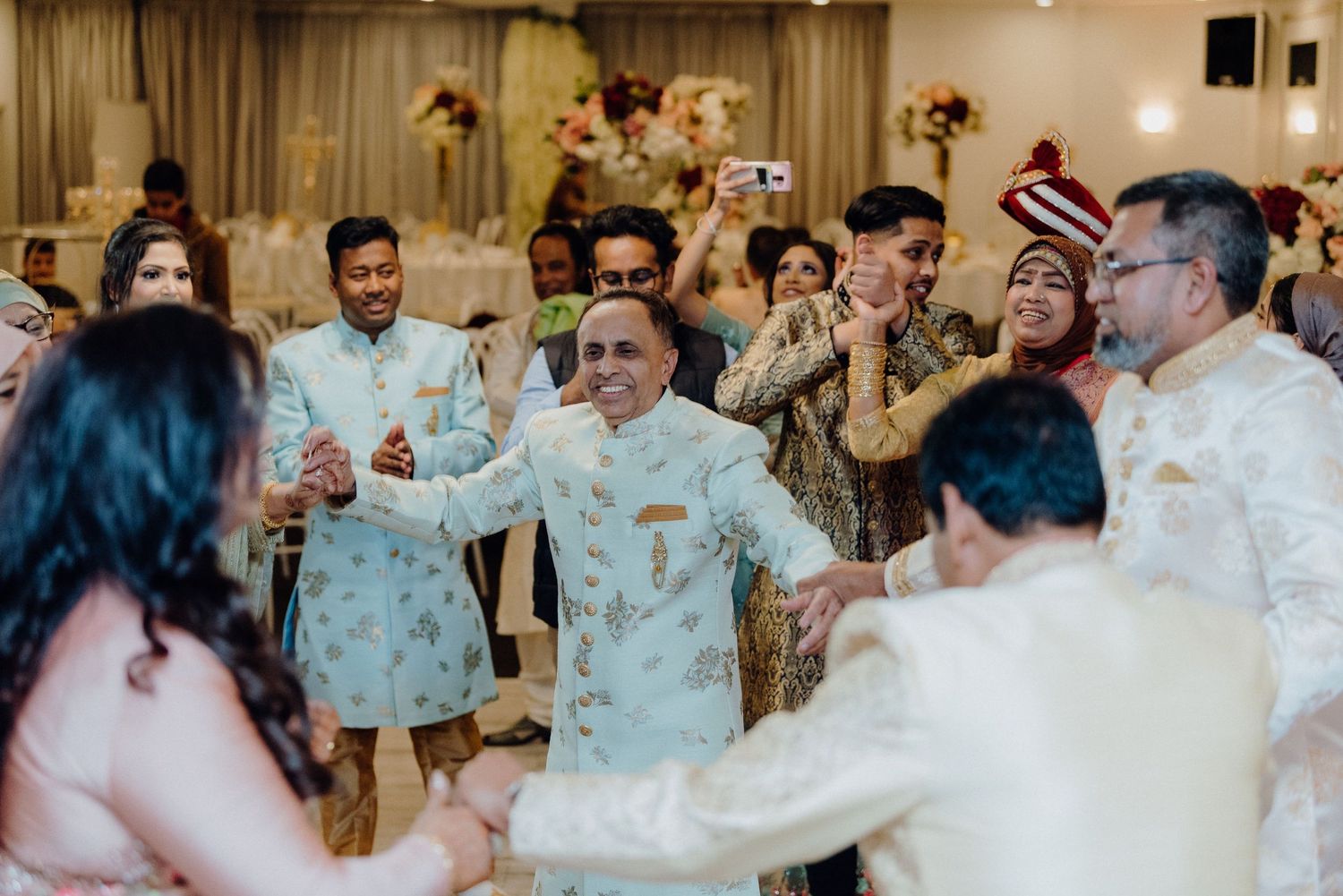 Guests dancing and celebrating at a joyous wedding reception in traditional formal attire.