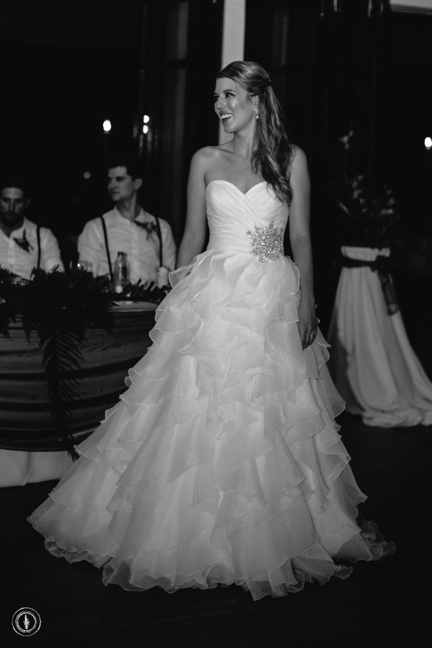Bride in ruffled ballgown poses elegantly during evening wedding reception.