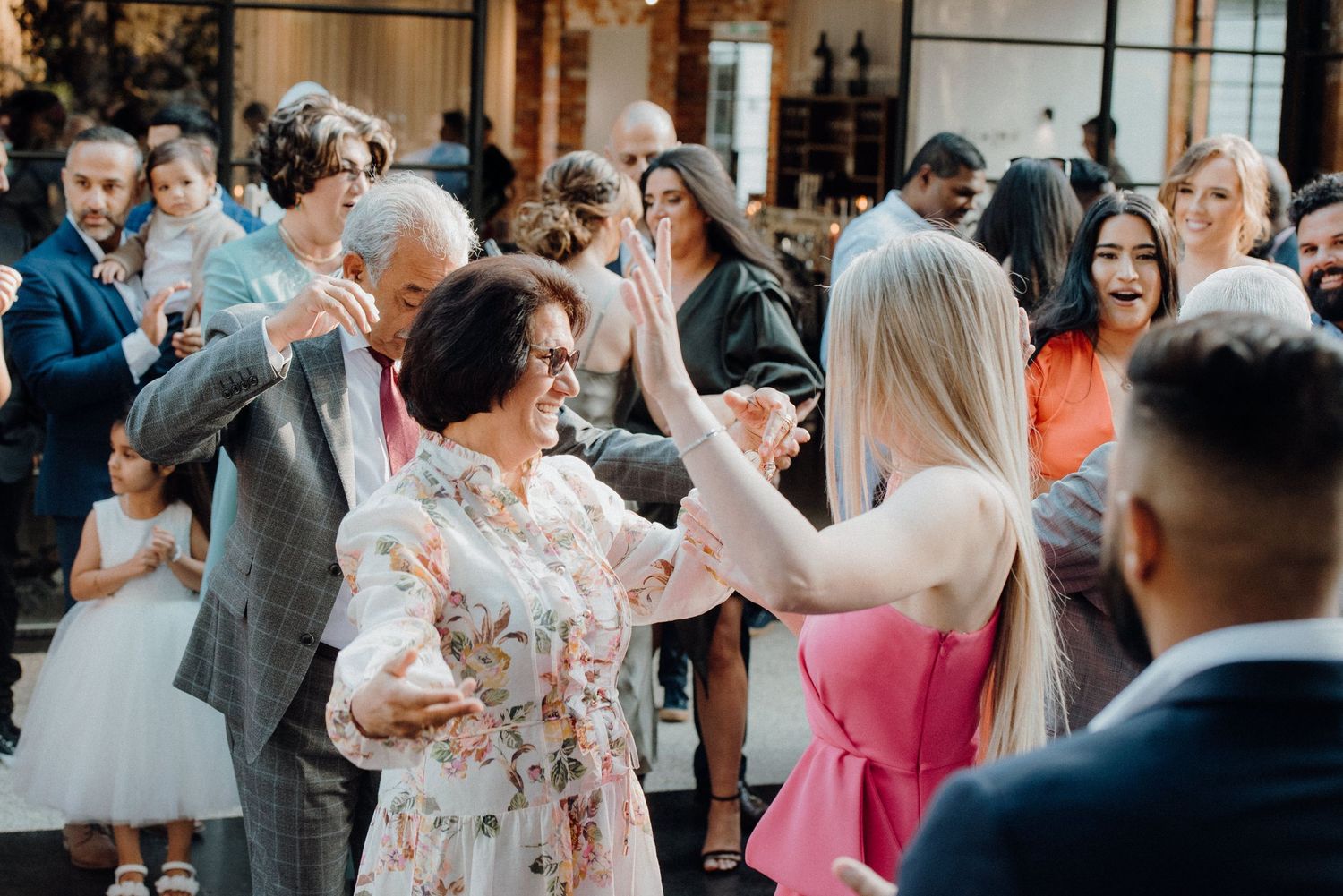 Wedding guests enjoying themselves while dancing at a lively indoor reception party.
