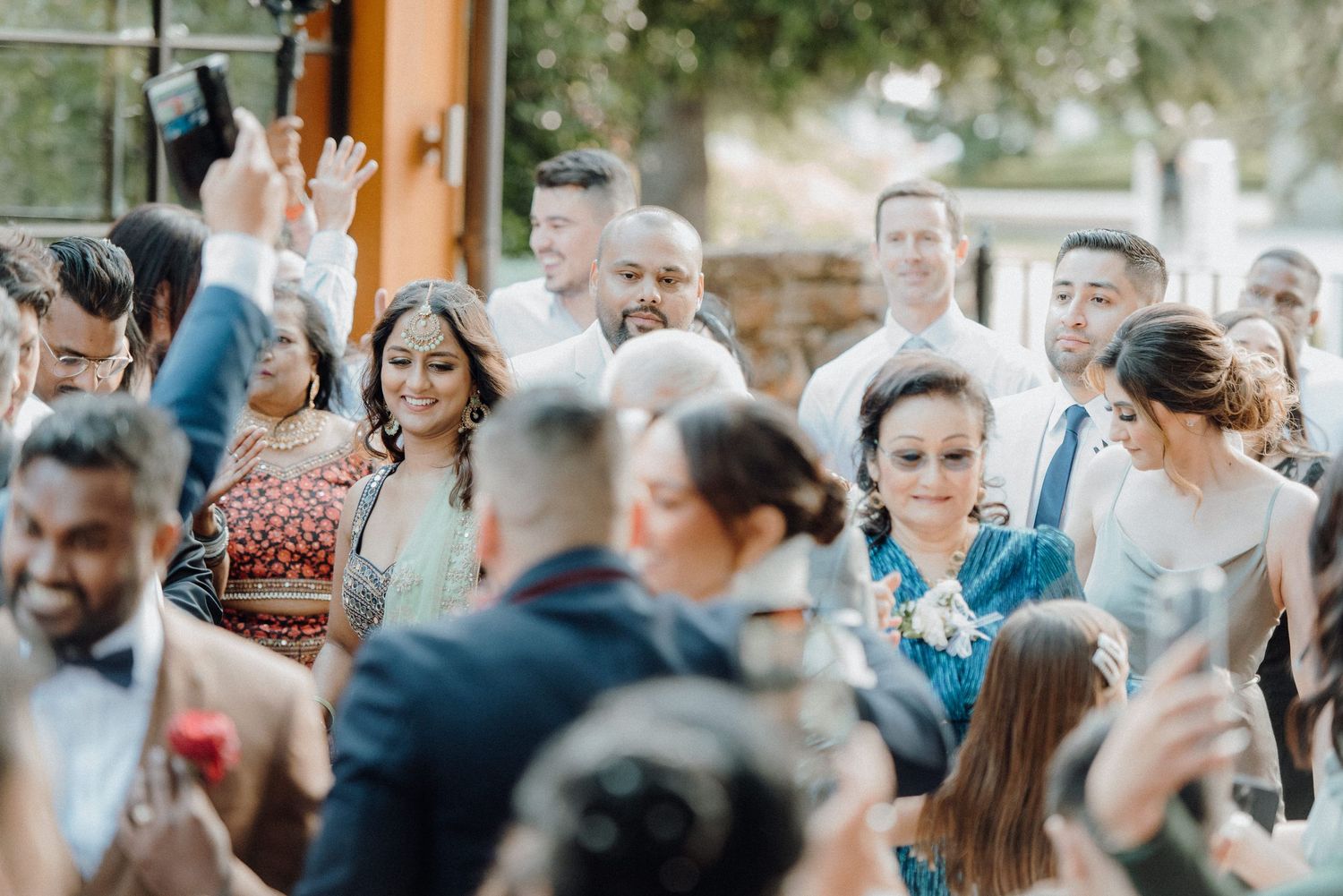 Wedding guests mingling and celebrating at an outdoor reception venue with natural lighting.