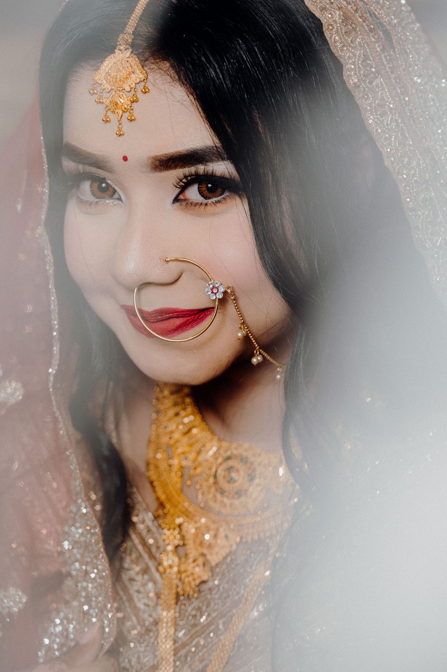 Close-up portrait showing traditional bridal jewelry and makeup in soft dreamy lighting.