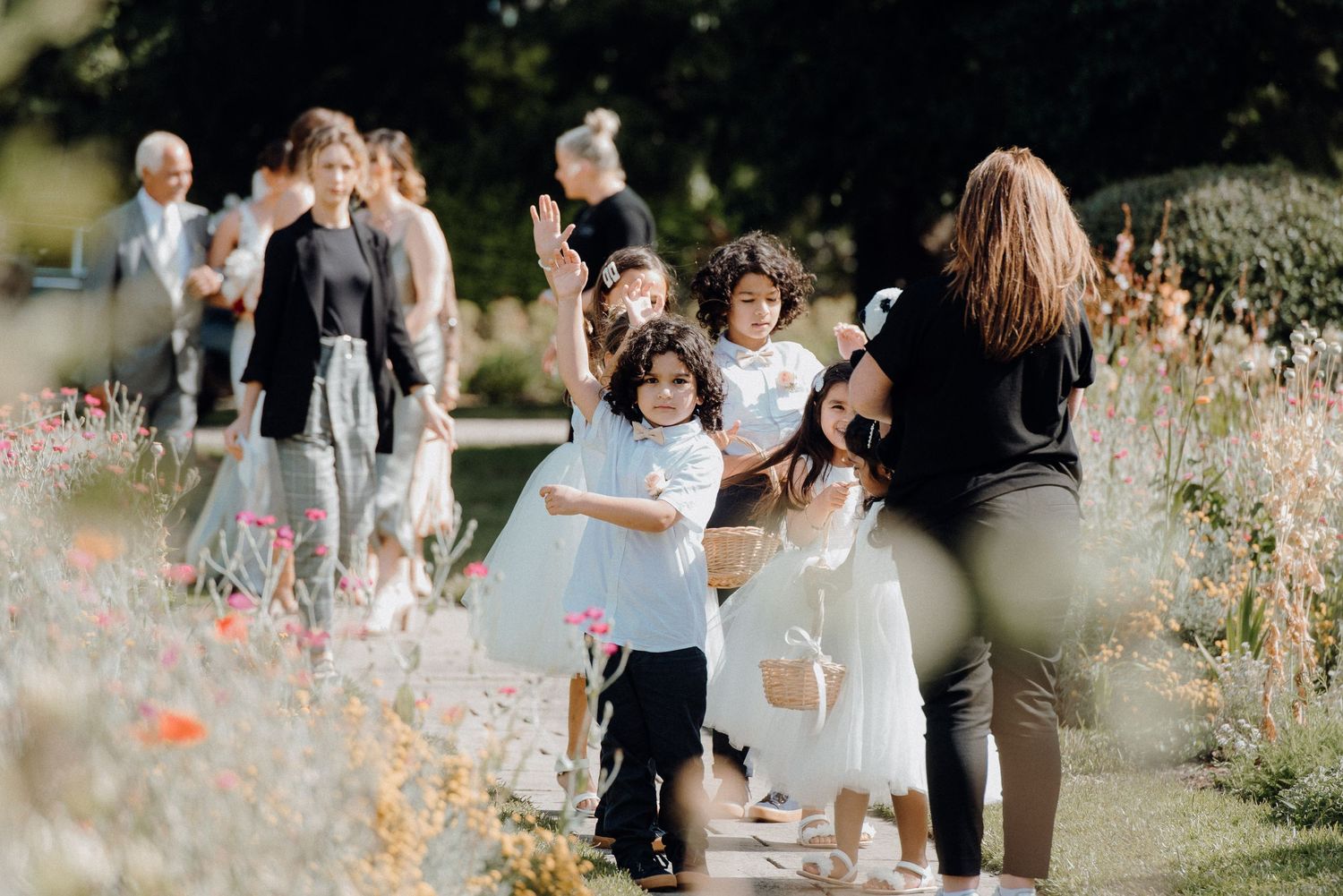 Wedding party and children walking through wildflower garden path.