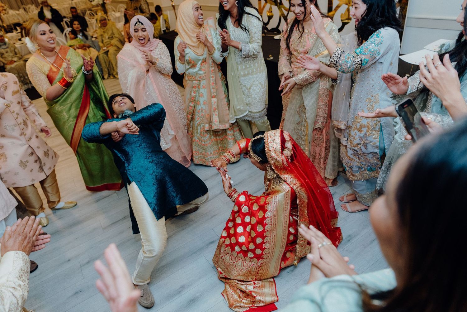 Energetic dancing and celebrations at a multicultural wedding reception with colorful traditional outfits.