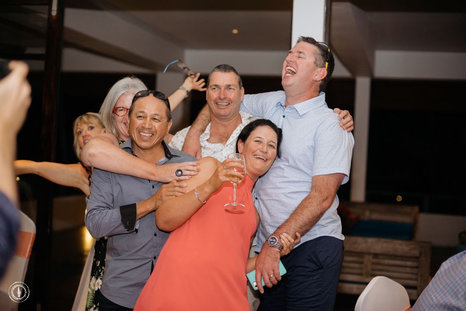 A group of wedding guests laughing and embracing during a celebration.