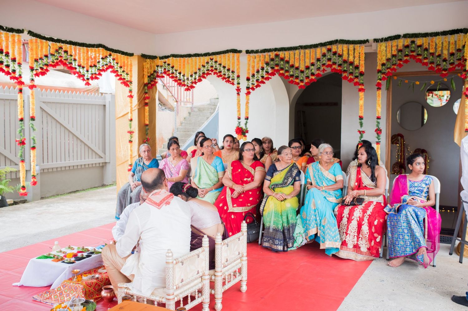 Wedding guests in colorful saris seated during traditional Indian ceremony.