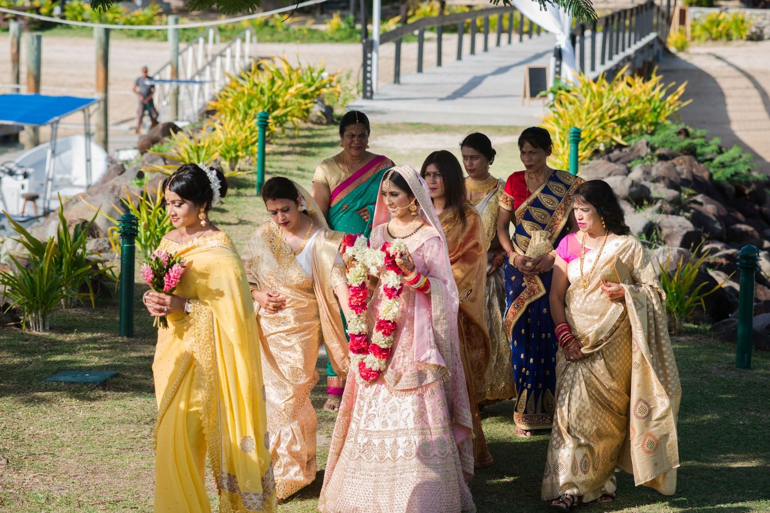 Bridesmaids in colorful traditional Indian attire walking together at an outdoor venue.