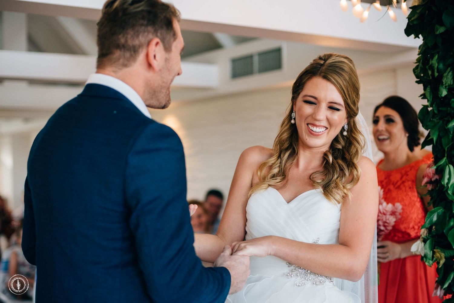 Joyful moment during wedding ceremony as couple exchanges vows under indoor lighting.