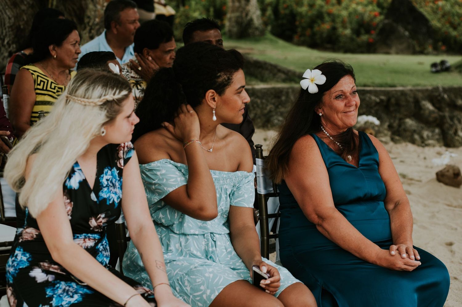 Wedding guests in summer attire seated at an outdoor tropical ceremony.