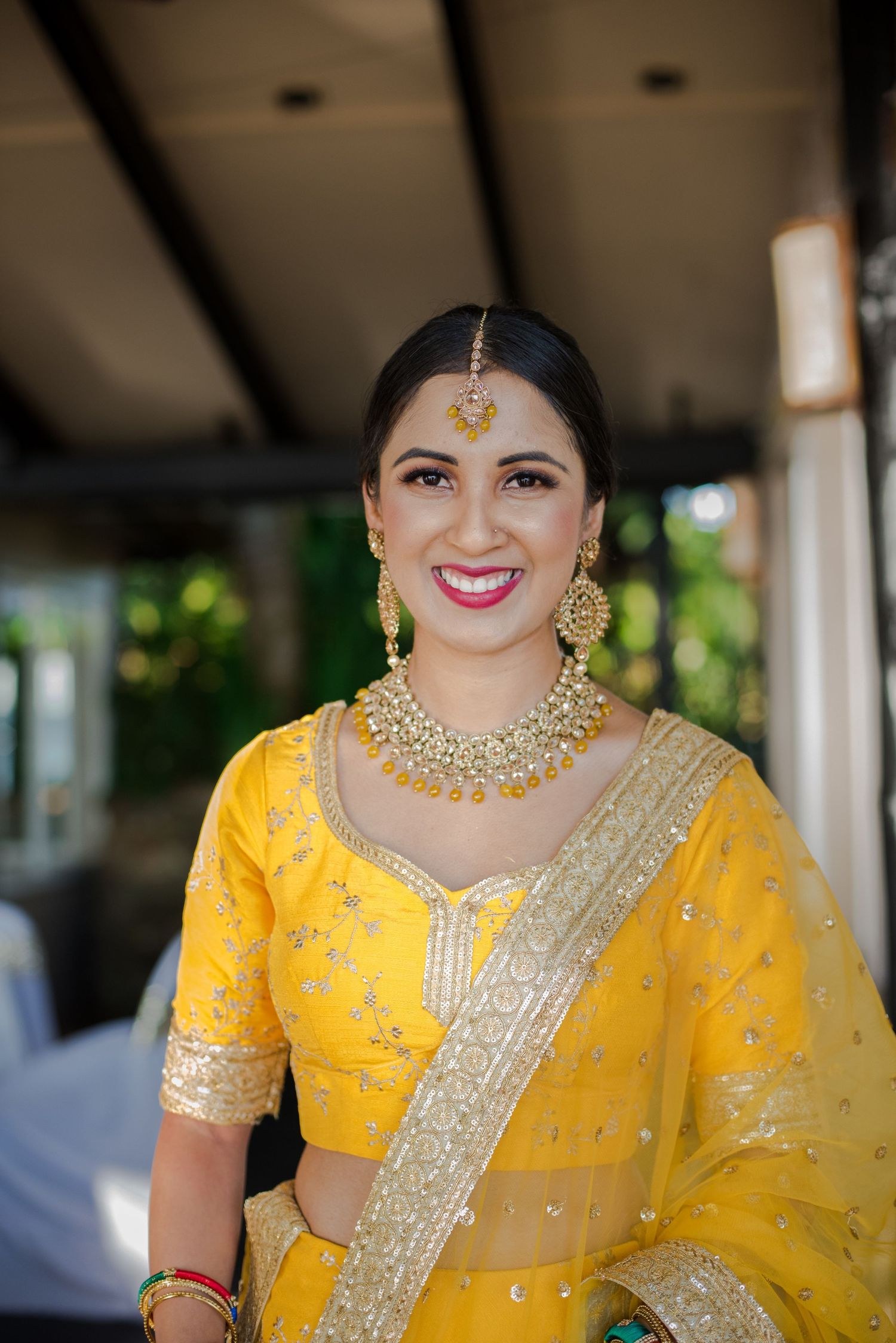 Traditional Indian bridal attire featuring yellow lehenga and ornate jewelry.