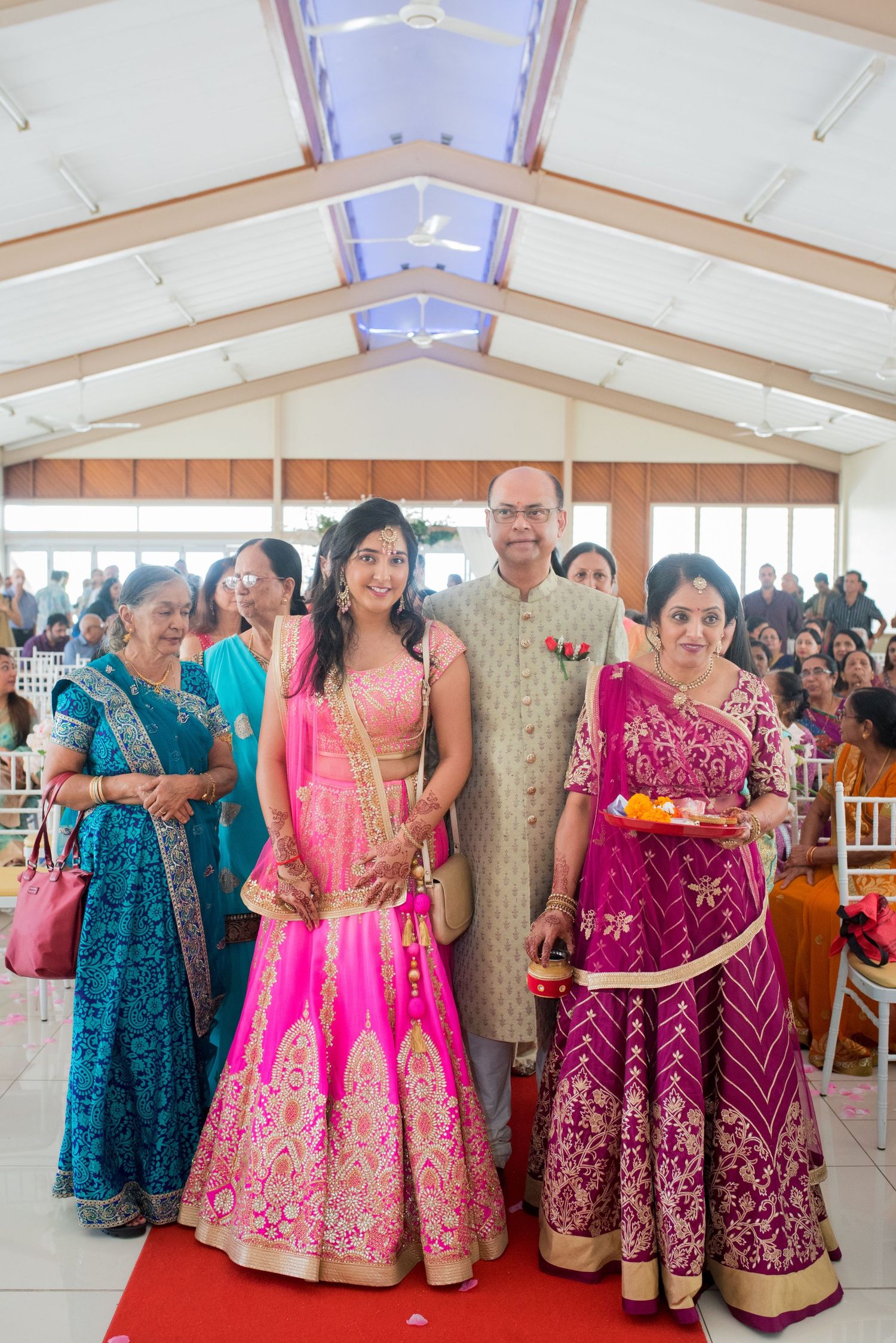 Family members in vibrant traditional Indian outfits posing together in an elegant venue.