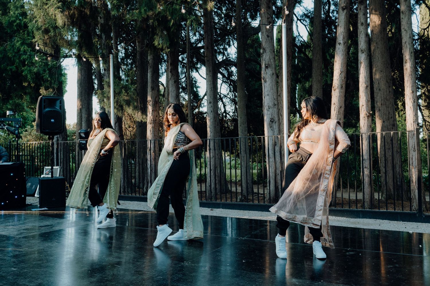 Dancers in flowing dresses performing choreographed moves on an outdoor stage.