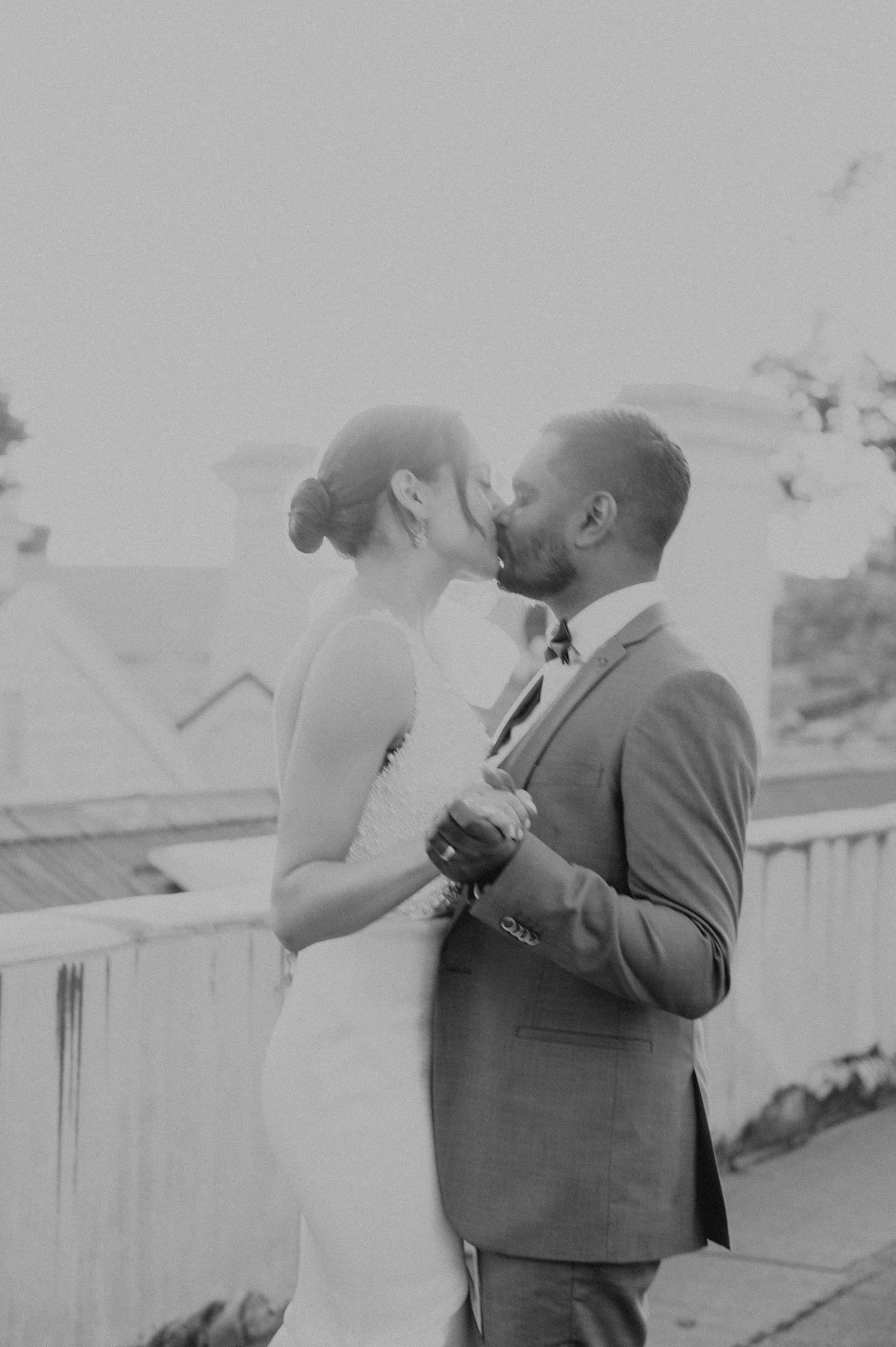 Black and white portrait of tender wedding moment on rooftop terrace.