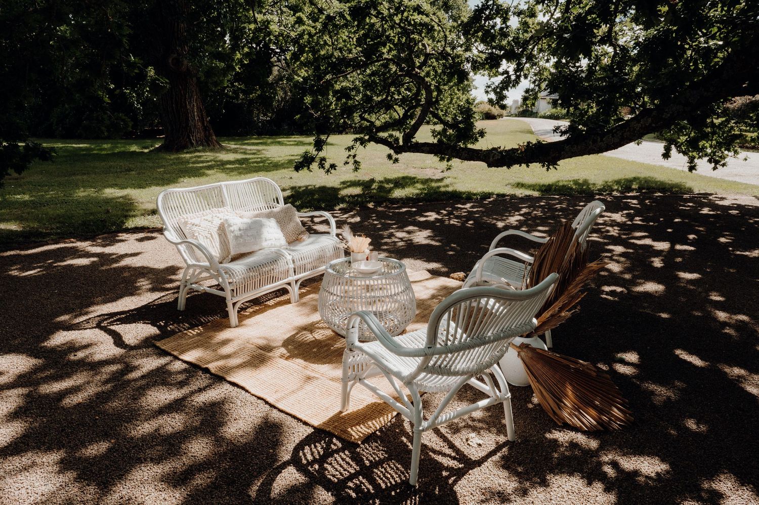 White wicker chairs arranged on a shaded lawn for outdoor seating.