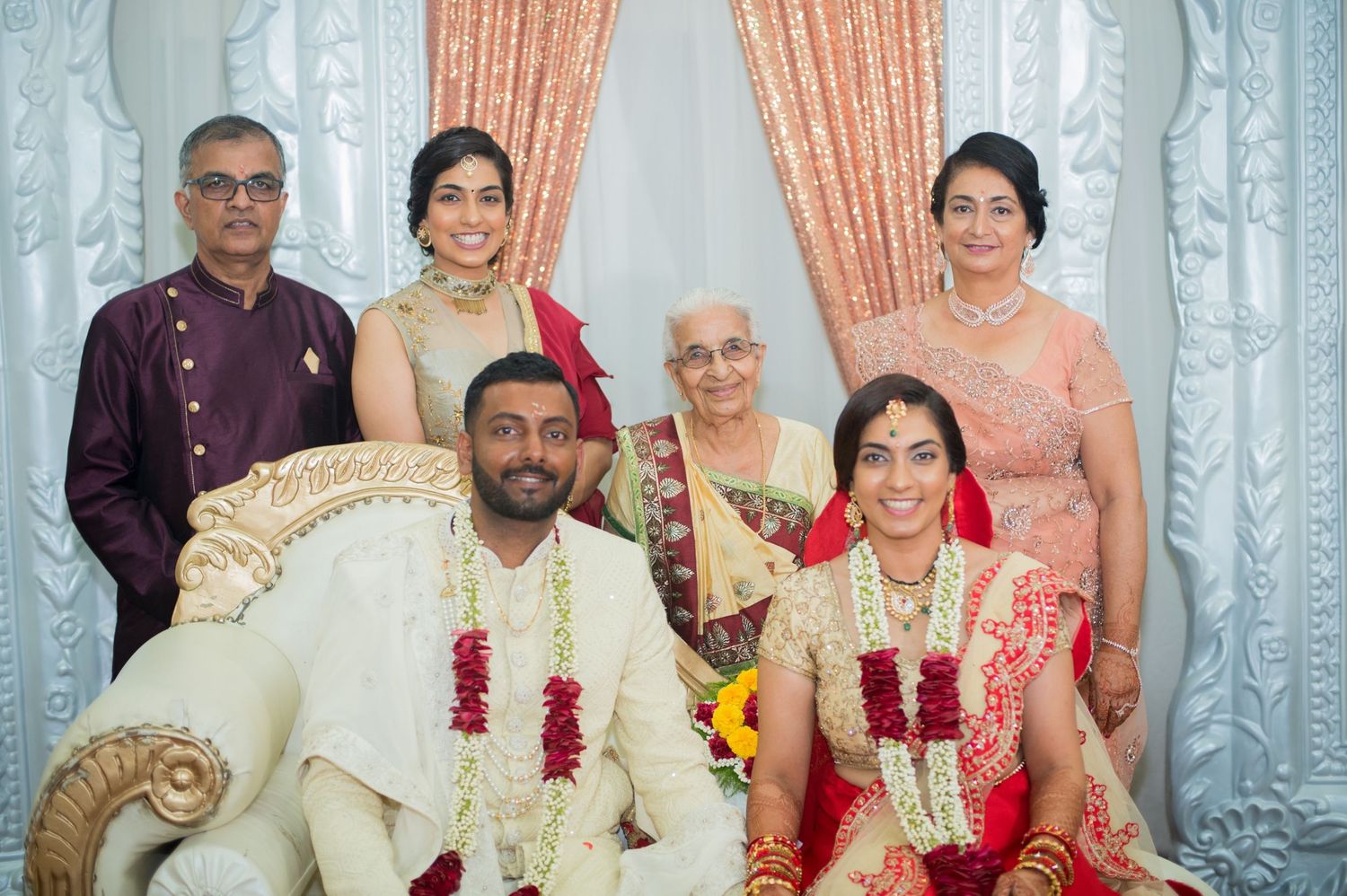 Family portrait during a traditional South Asian wedding ceremony with elegant decor.