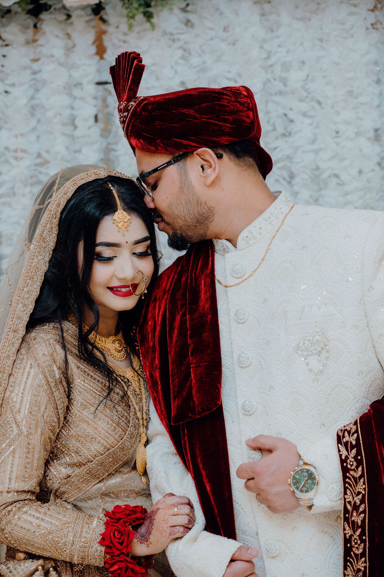 Intimate moment between couple in South Asian wedding attire.