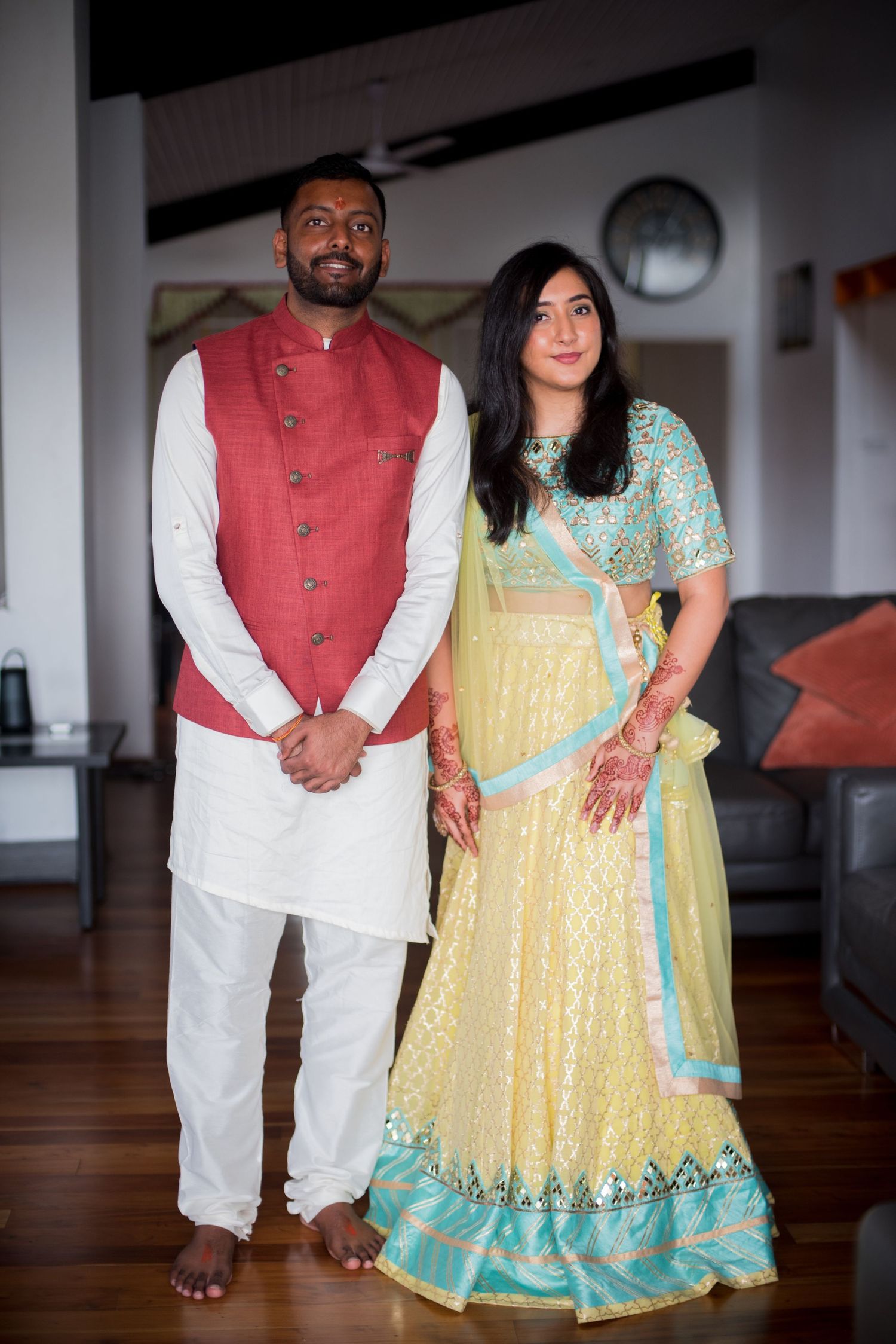 Couple in traditional Indian wedding attire posing together indoors.