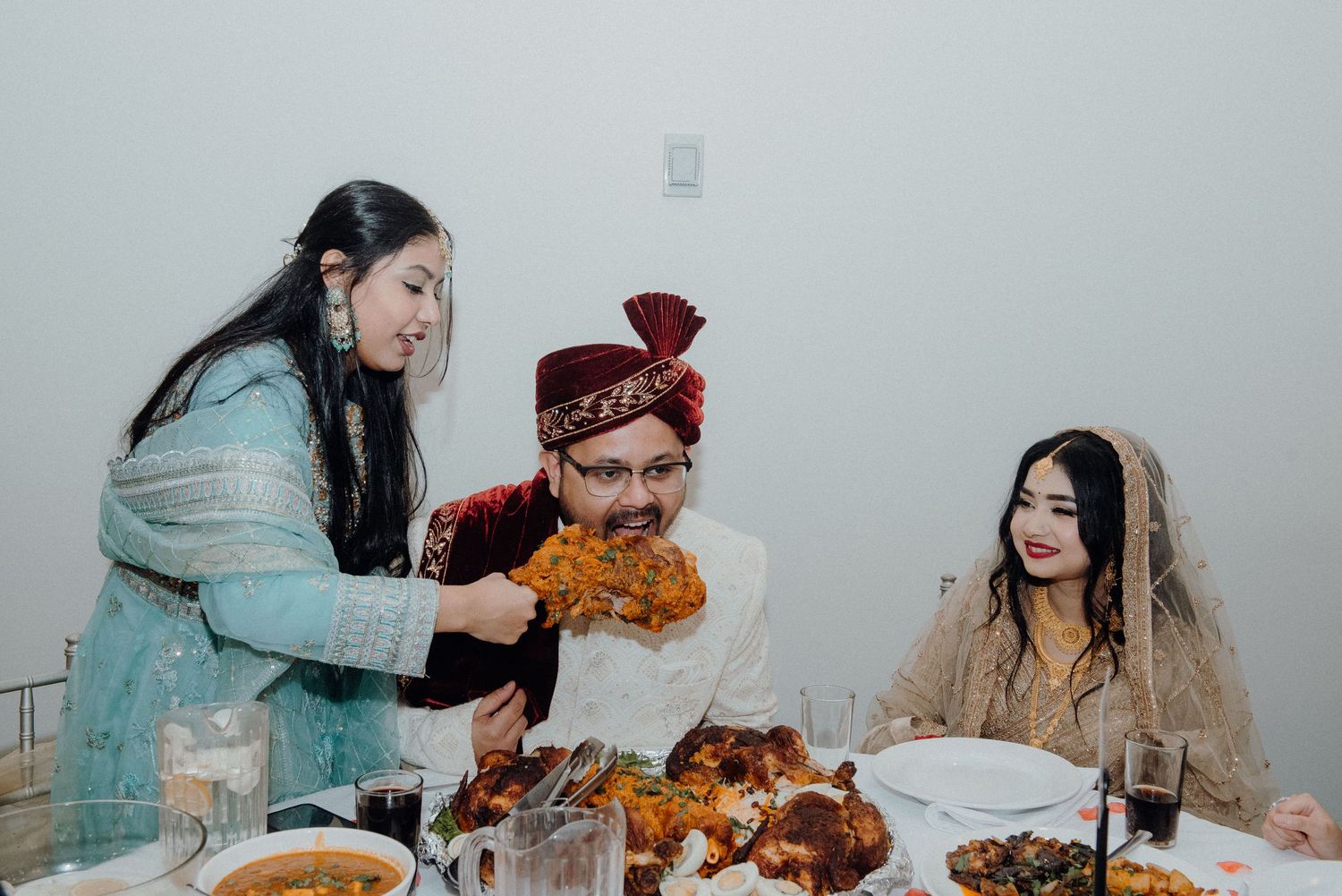Wedding guests sharing traditional Pakistani cuisine at a decorated dining table.