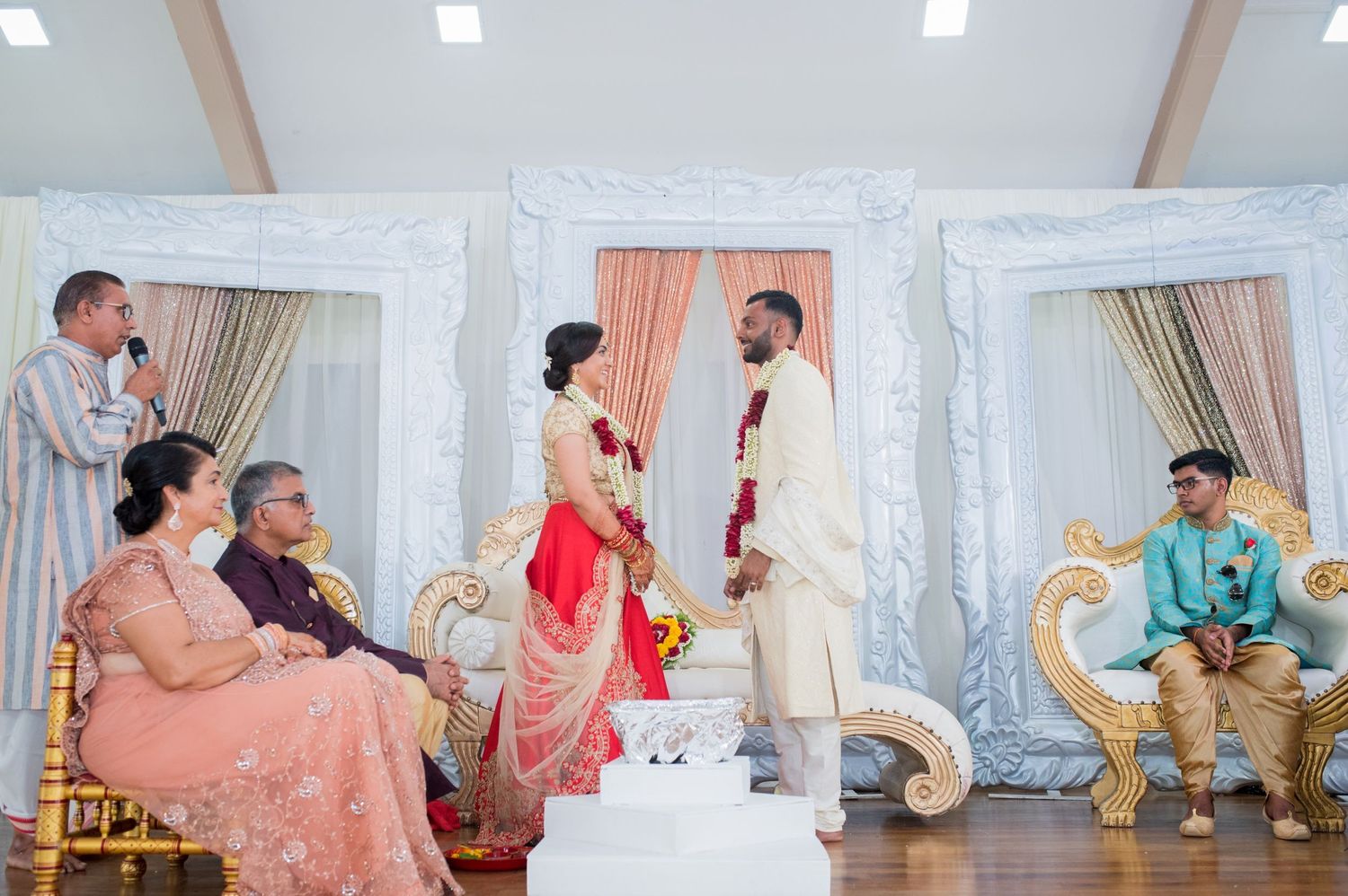 Wedding ceremony setup with multiple ornate white frames and peach curtains as backdrop.